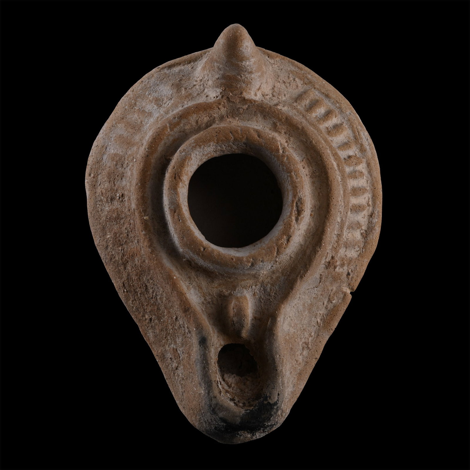 Late Roman Terracotta Oil Lamp: Circa 5th-7th century A.D. Piriform body with raised ridges and linear decoration on the shoulder, conical handle at the rear, branch motif below the nozzle and a pellet at the centre of the base. 54.