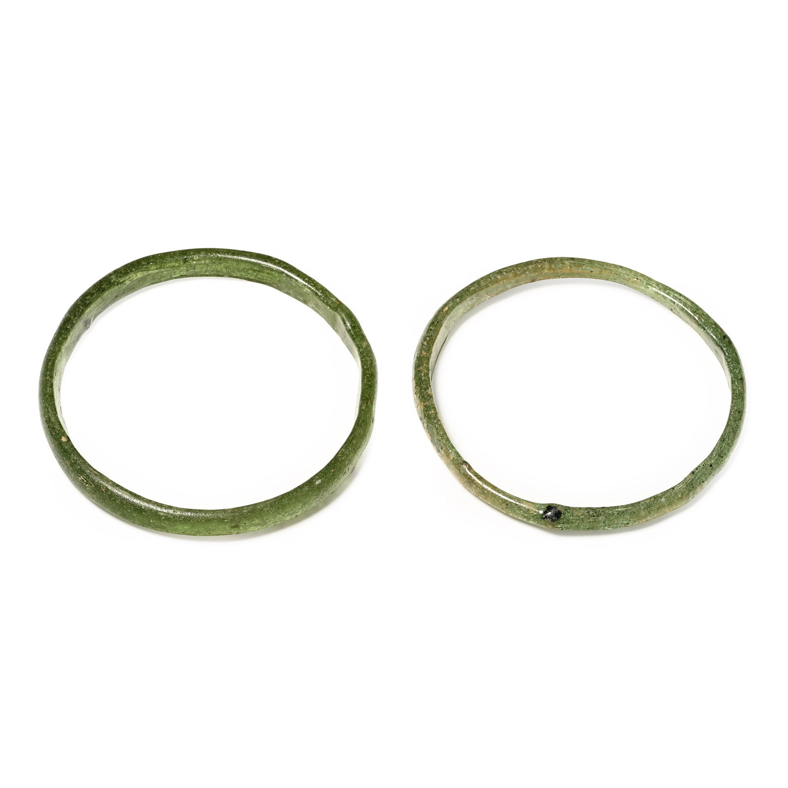 Roman Green Glass Bangle Pair: 1st-4th century A.D. Each plano-convex in section in green glass with striated surface. 23 grams total, 72-75 mm (2 7/8 in.). [2, No Reserve] Acquired on the UK art market in the late 20th century A.D
