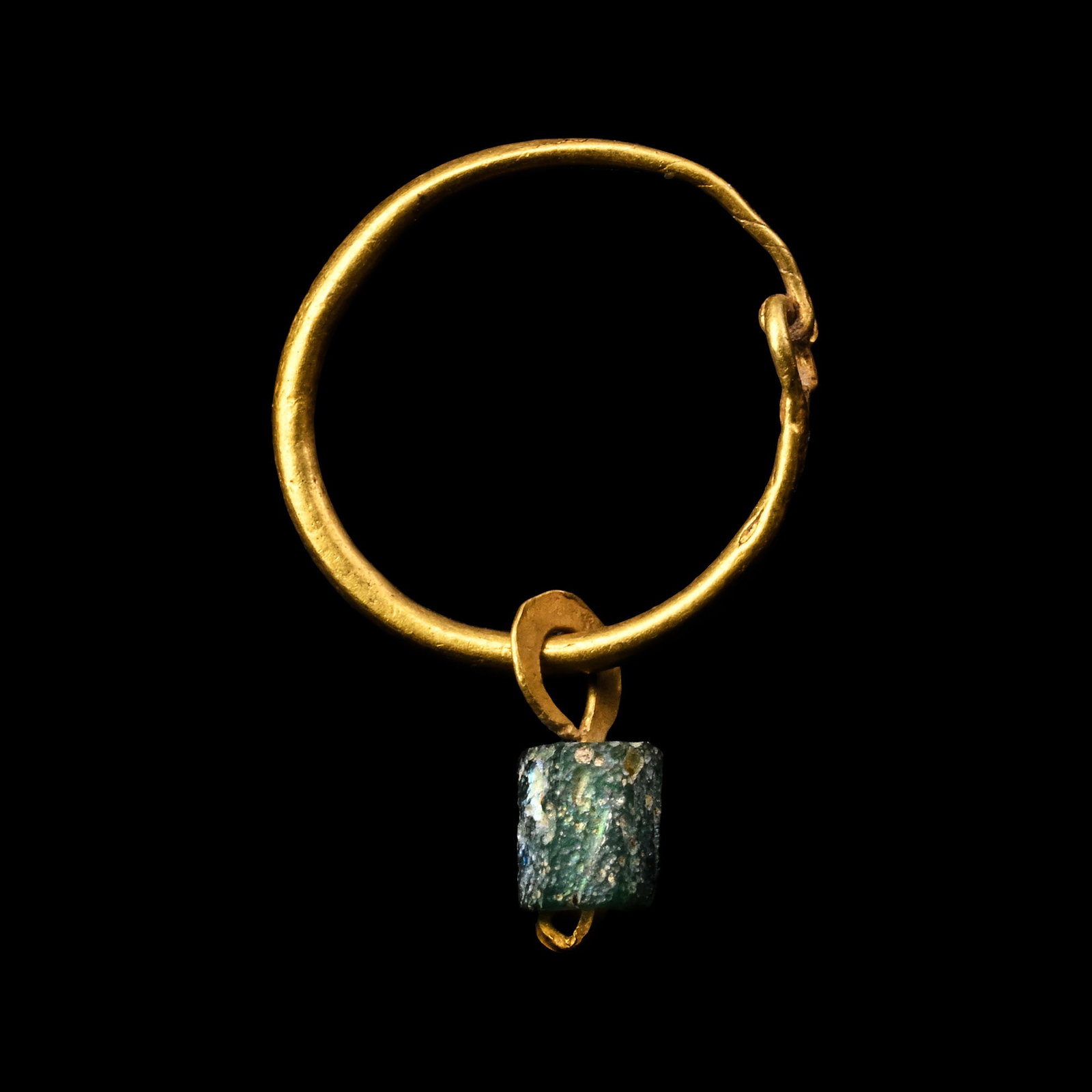 Roman Gold Earring with Emerald-Coloured Bead: 1st-4th century A.D. Comprising a round hoop with a loop closure and an emerald-coloured glass bead. 0.66 grams, 23 mm (7/8 in.). [No Reserve] From the private collection of a European gentleman (1942