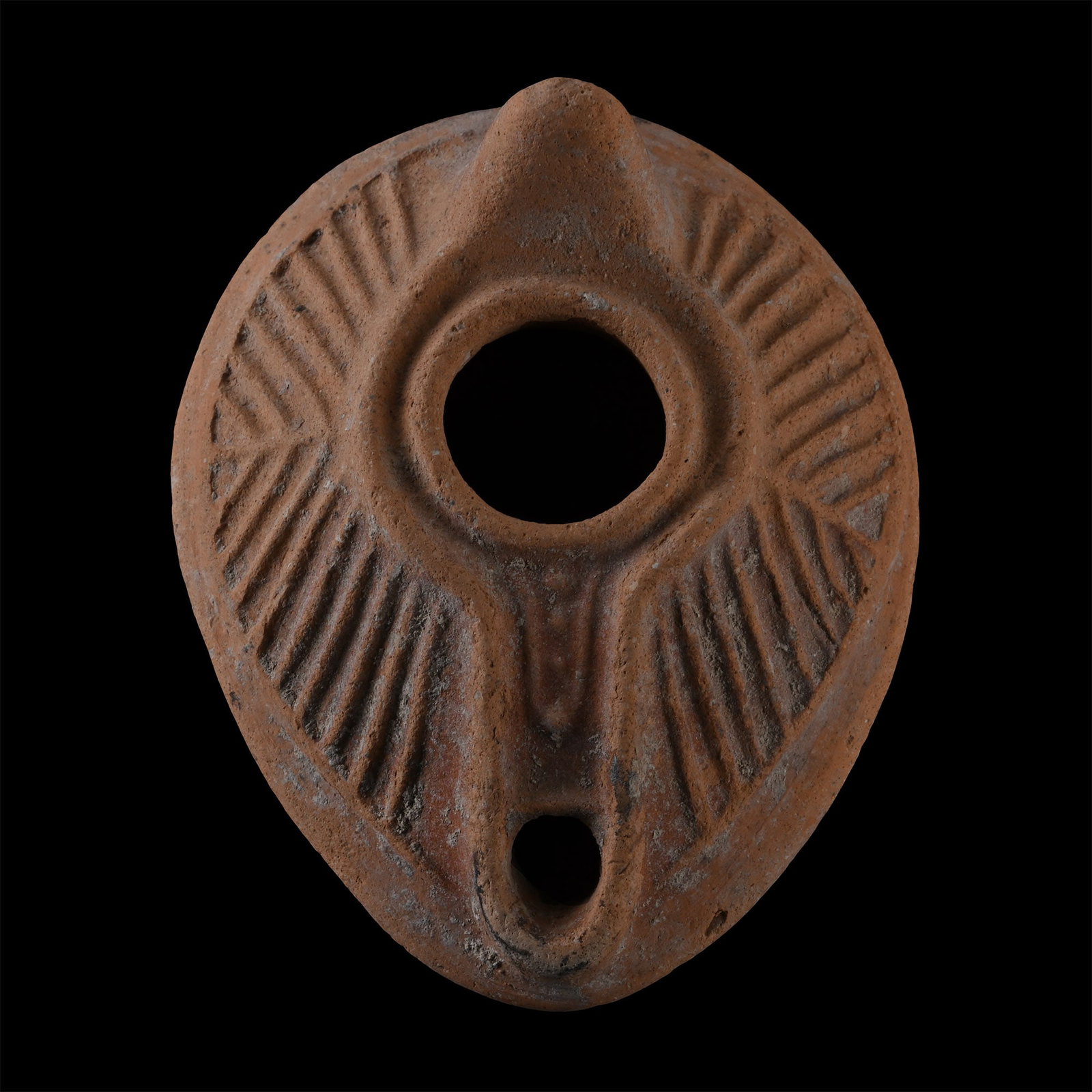 Byzantine Period Terracotta Oil Lamp: Circa 5th-7th century A.D. Piriform body with short nozzle and a stub handle on the rear, raised linear decoration on the body, base with a sunwheel motif. 100 grams, 89 mm (3 1/2 in.). [No Reserve] F