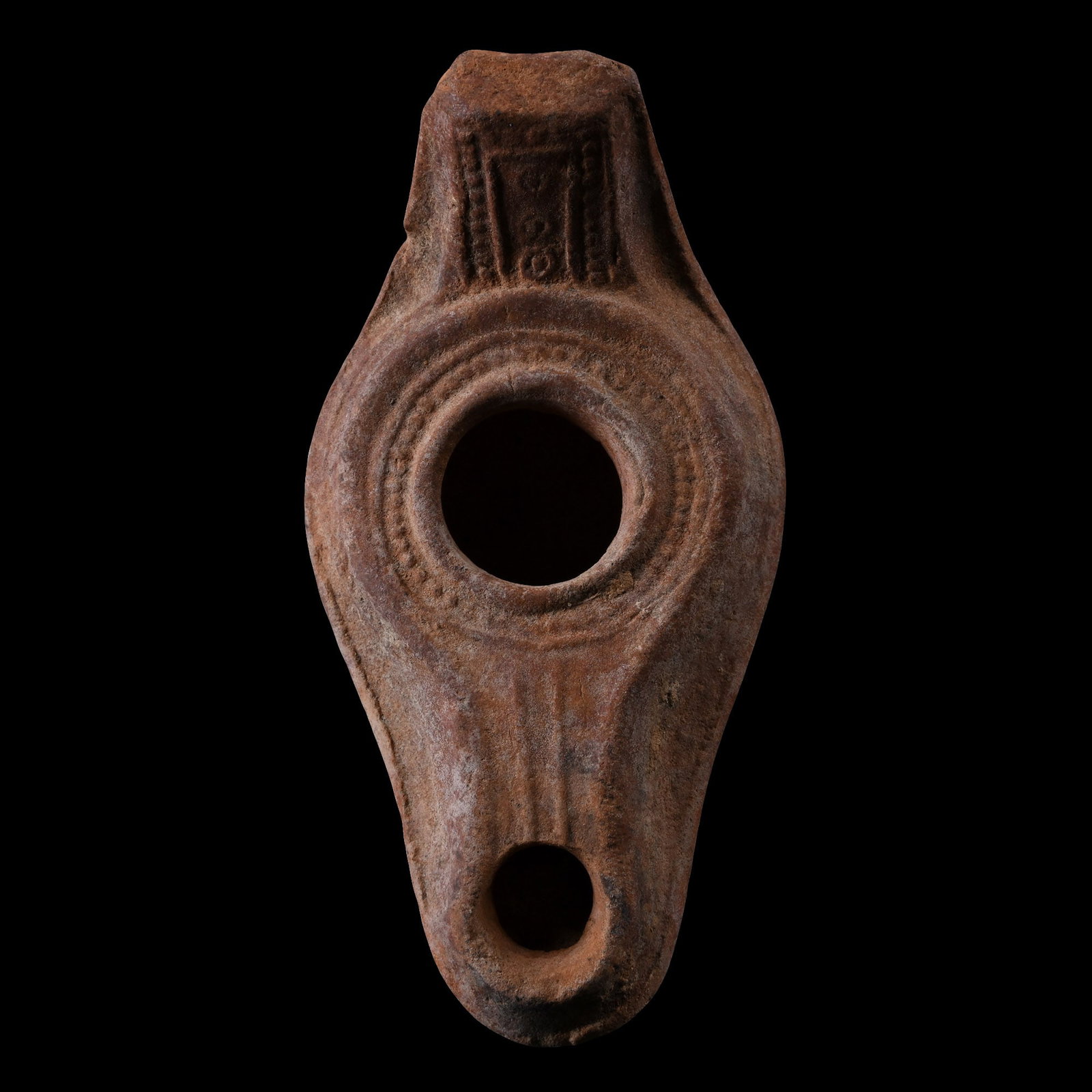 Byzantine Period Terracotta Oil Lamp: Circa 5th-7th century A.D. Slipper type with a wide nozzle and a raised handle with pellet and ring-and-dot decoration to the rear, three vertical bands behind the handle, a band of pellets surroundin