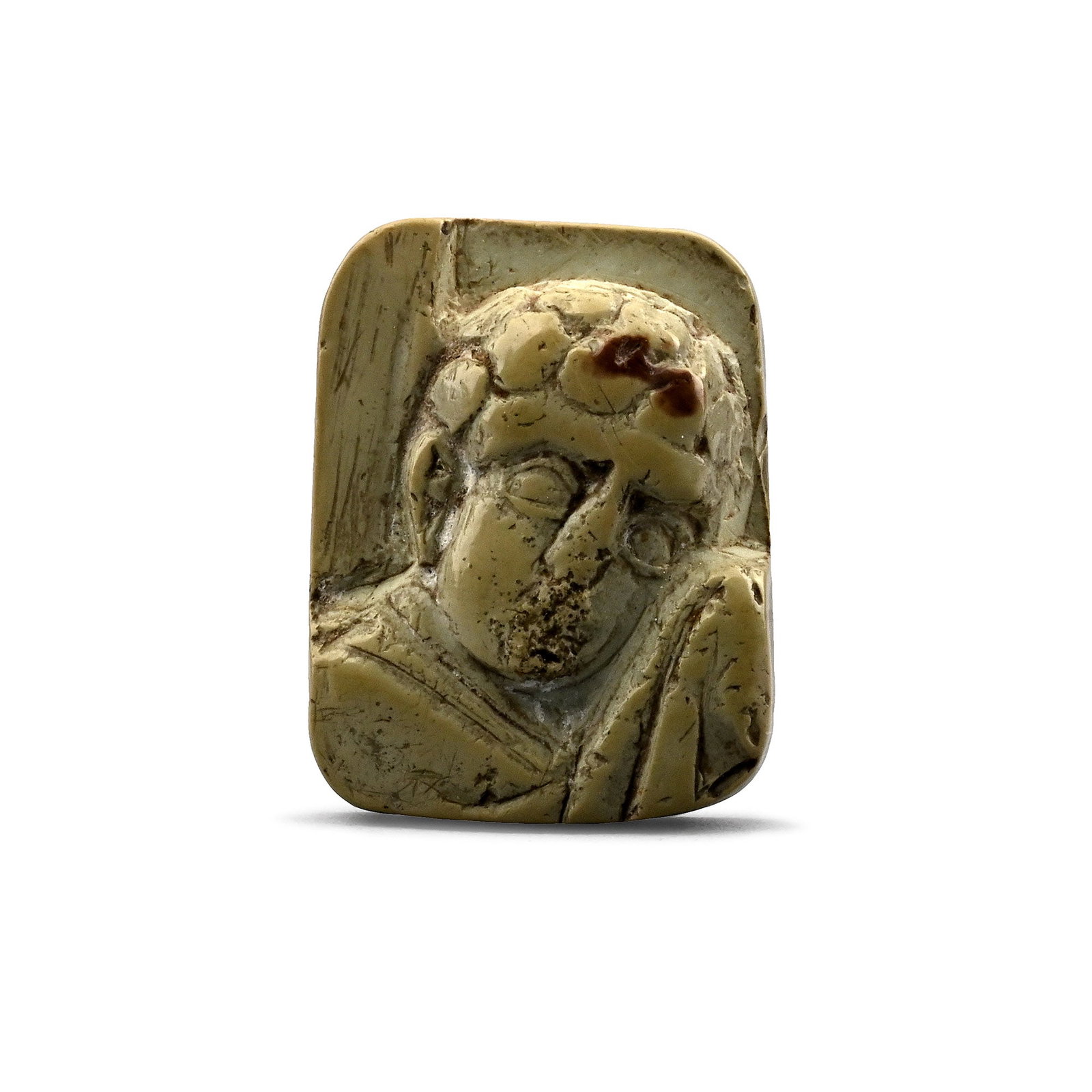 Byzantine Steatite Mount with Saint John the Theologian: 10th-12th century A.D. Showing a bust of a man dressed in a cloak and with his head turned to look over his right shoulder, possibly depicting St John; rectangular in plan with rounded corners. Cf. Ka