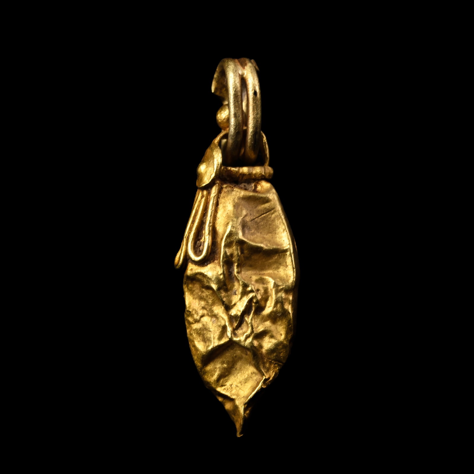 Western Asiatic Oval Gold Pendant: 1st millennium B.C. Comprising a hollow-form leaf-shaped pendant with applied filigree loops and a small boss beneath the ribbed suspension loop. 0.58 grams, 19 mm (3/4 in.). [No Reserve] Ex private B