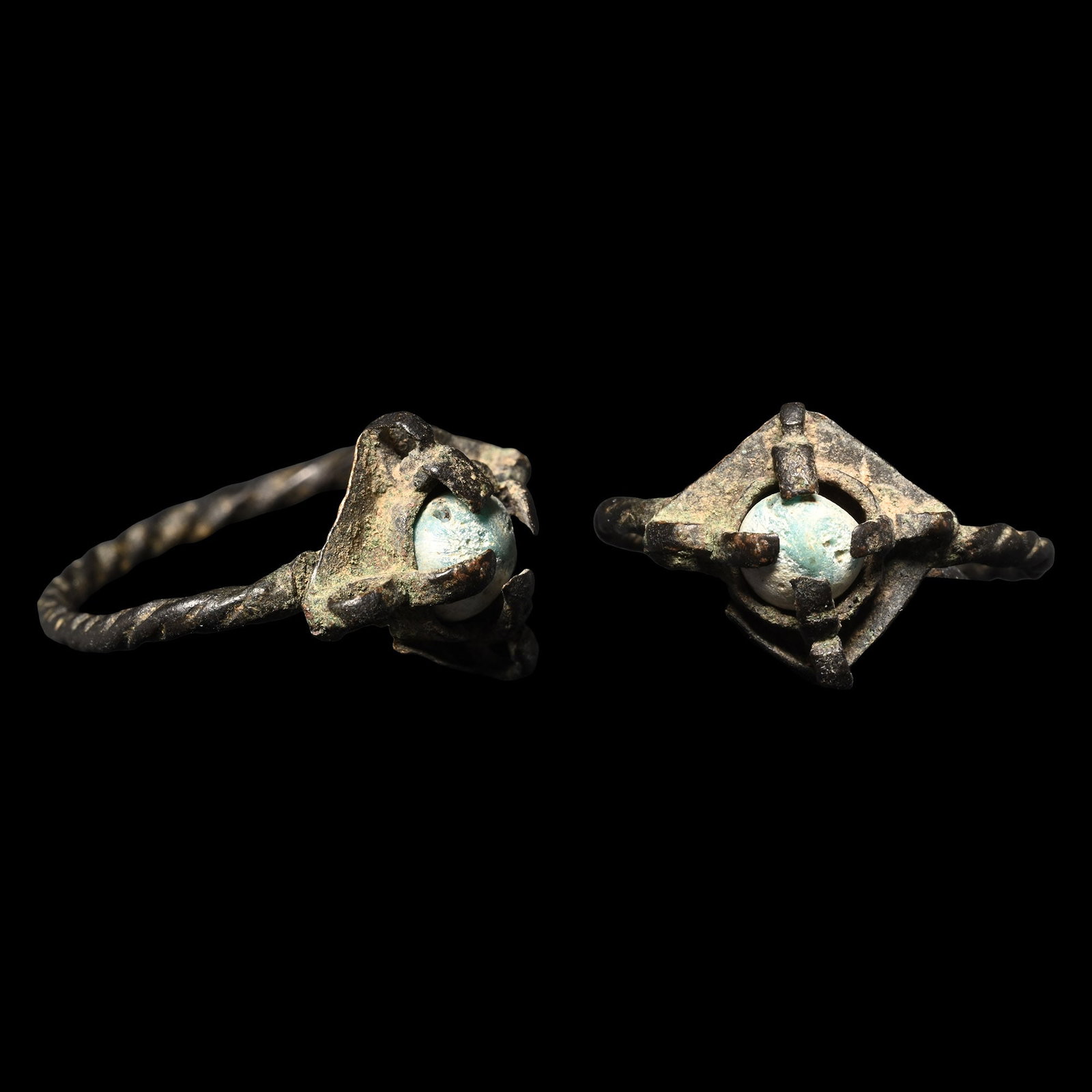 Viking Age Bronze Ring with Cabochon: Circa 9th-12th century A.D. Comprising a twisted hoop and a lozenge-shaped bezel plaque with four claws holding a blue glass cabochon. 1.79 grams, 23.79 mm overall, 17.81 mm internal diameter (approxi