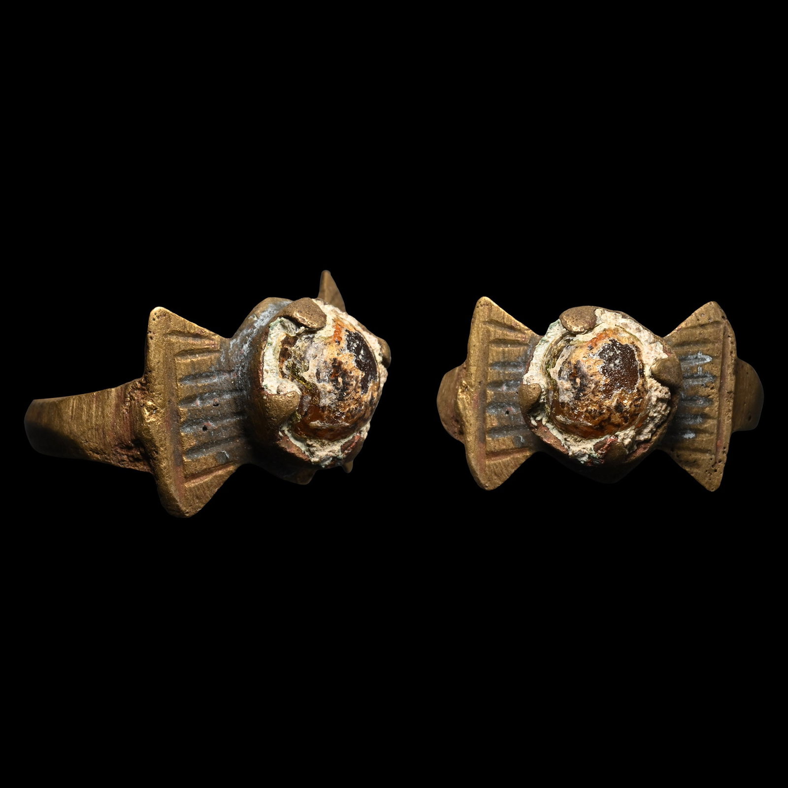 Viking Age Bronze Ring with Cabochon: Circa 9th-12th century A.D. Comprising a D-section hoop with flared plaques on the shoulders, a circular bezel with claws, set with an amber-coloured glass cabochon. 3.12 grams, 23.33 mm overall, 16.6