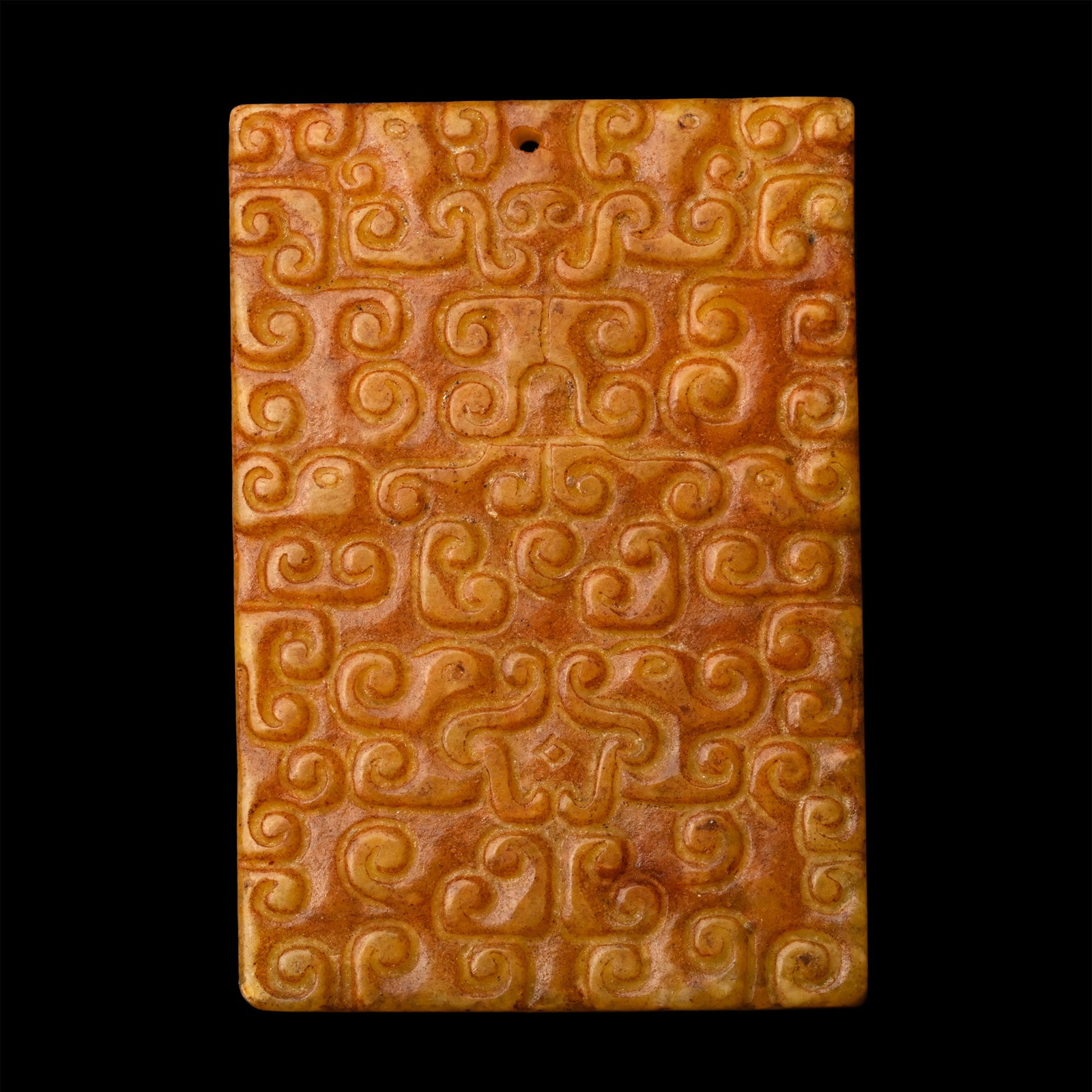 Chinese Amuletic Glass Pendant: 20th century A.D. A bifacial rectangular plaque pierced through the upper edge, both sides with densely arranged scroll motifs. 27.1 grams, 59 mm (2 1/4 in.). [No Reserve] Ex Paris gallery, France, 19