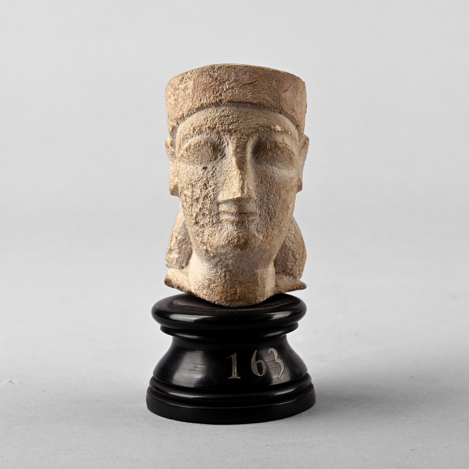 'The Metropolitan Museum of Art' Cypriot Limestone Votive Head of a Man: Circa 5th century B.C. Finely carved votive head with almond-shaped eyes and strong nose, lips set to a gentle smile, typical of the Greek kouroi of this period, wearing a conical headdress leaving th