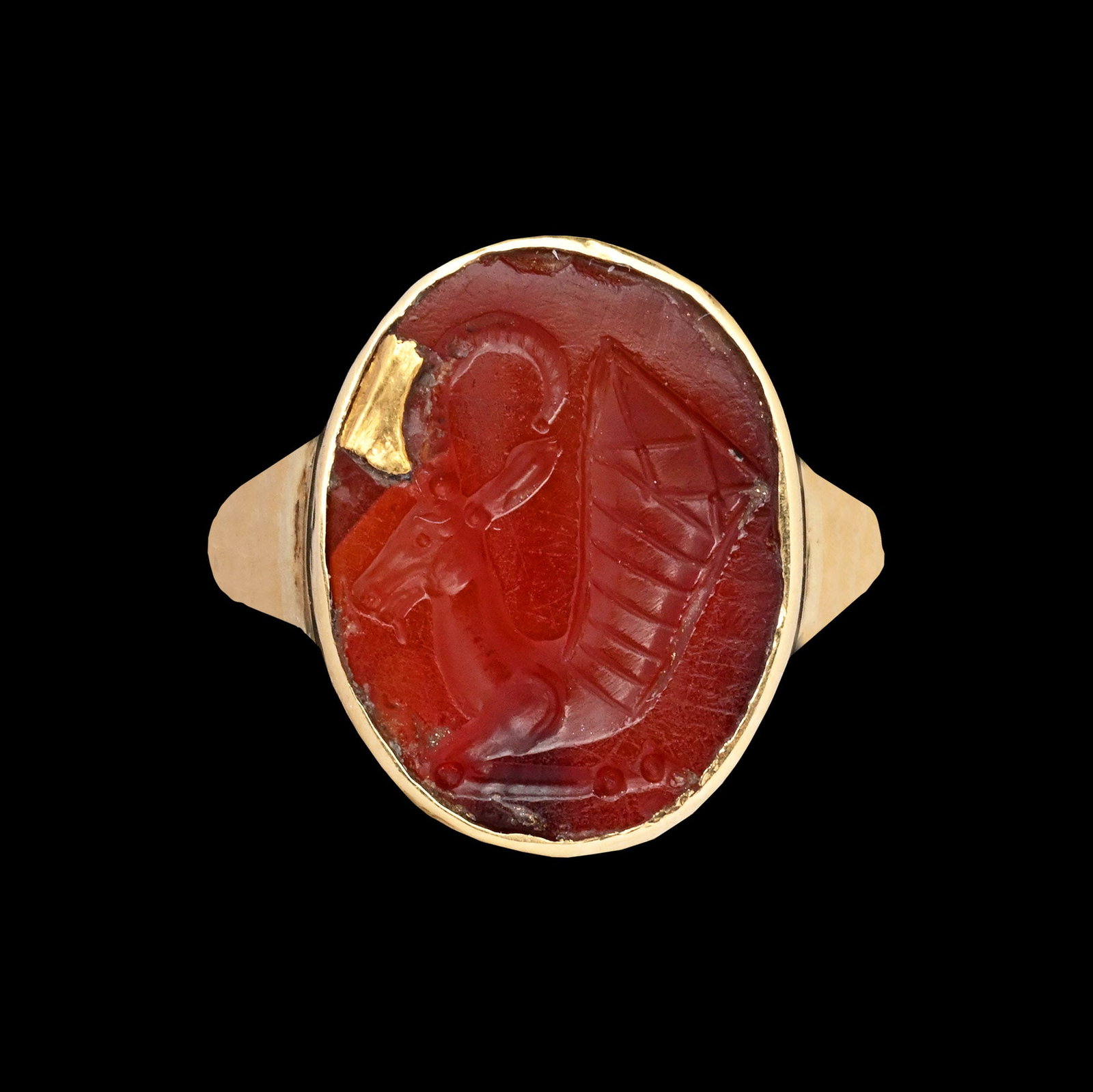 Parthian Carnelian Gemstone of a Goat-Headed Rhyton in Gold Ring: 4th century B.C.-220 A.D. Achaemenid or Parthian oval intaglio engraved with a style standing at the threshold between natural and stiff rigid linear style, depicting a goat-headed rhyton, the vessel 