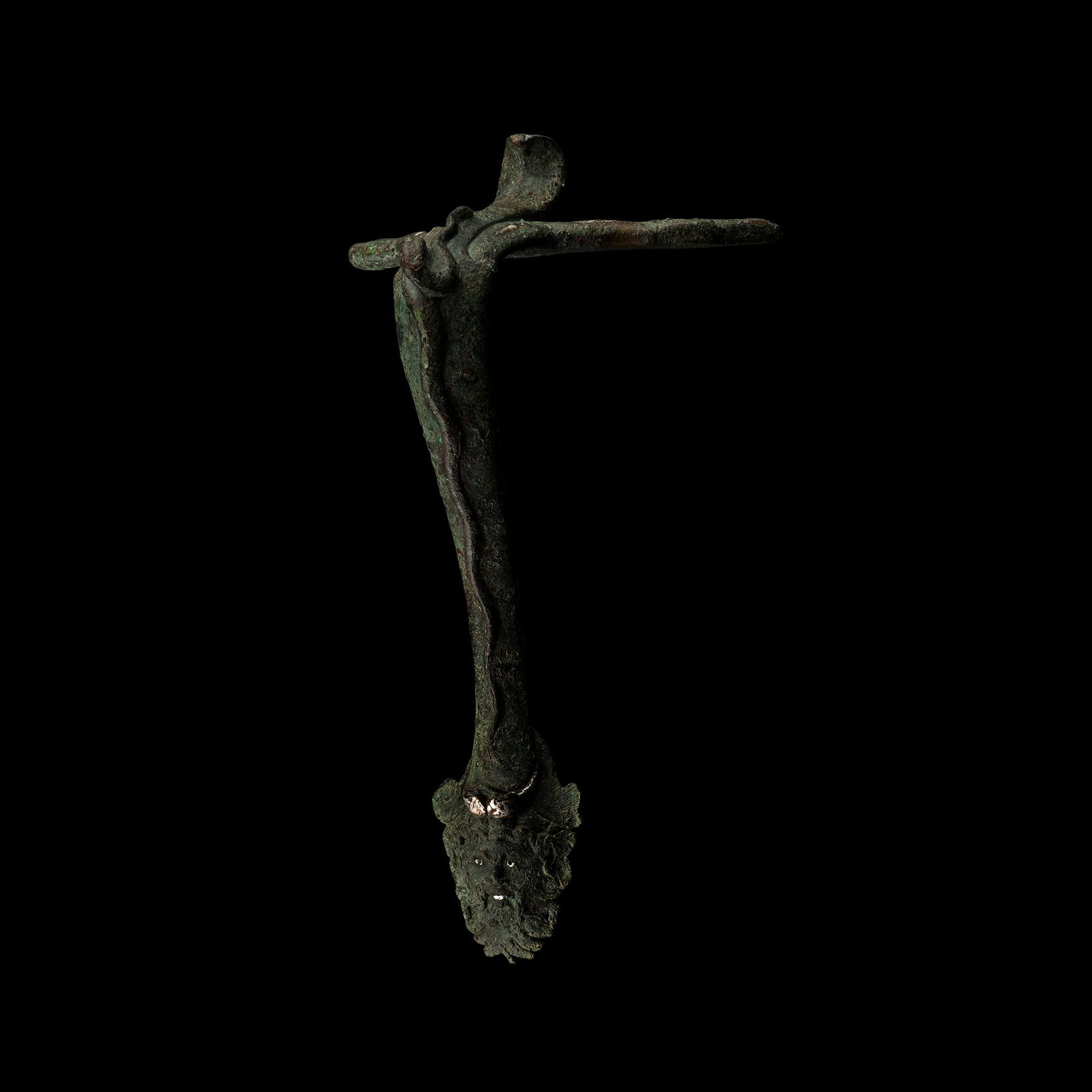 Roman Bronze Vessel Handle with Face: 1st century A.D. Swept in profile, comprising a horizontal crescentic panel to attach to the rim, with inlaid silver detailing, recurved cobra-shaped thumb pad, raised serpent to the outer face of the