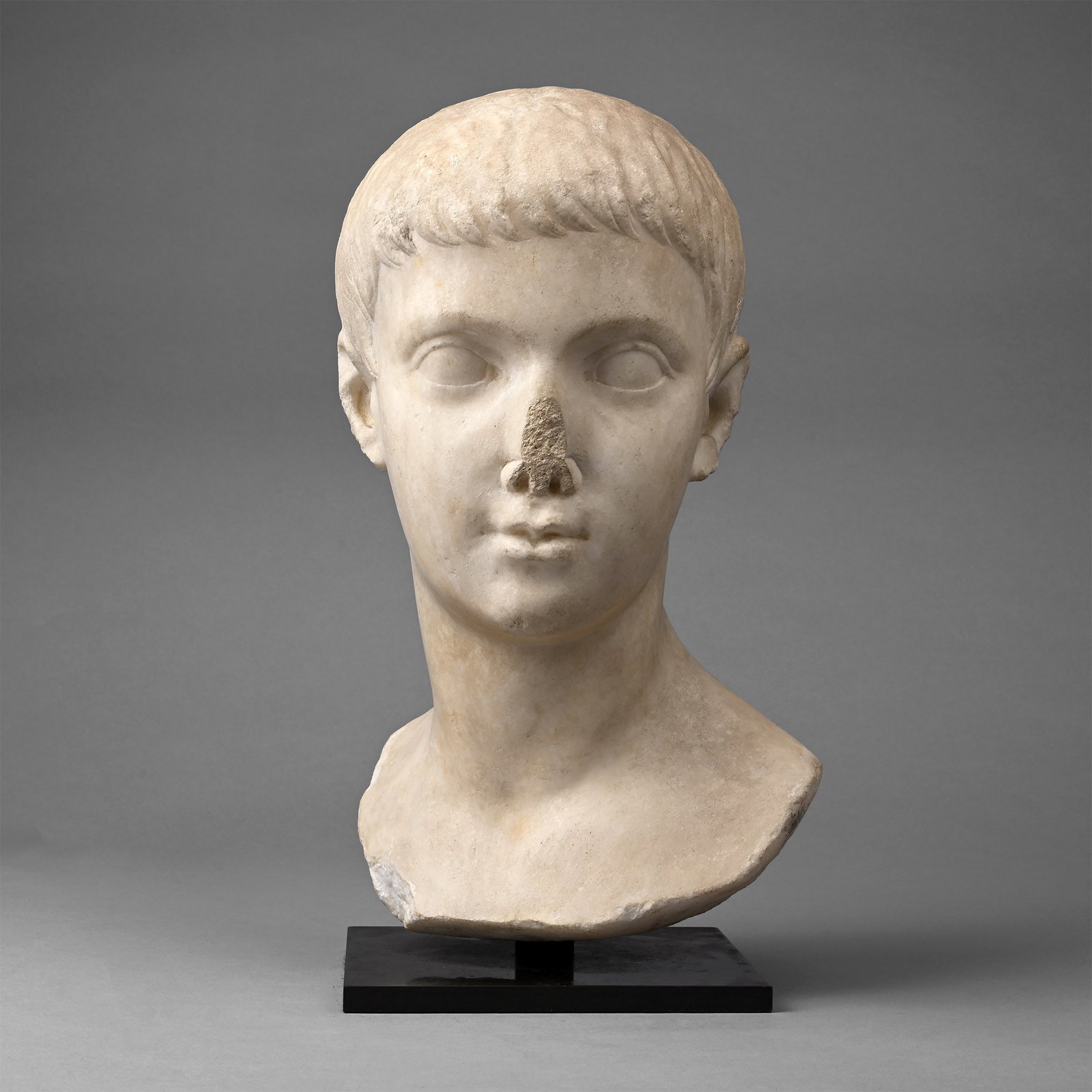 Roman Marble Portrait of Drusus the Younger: 13 B.C.-23 A.D. Finely carved bust of Drusus, son of Emperor Tiberius; the hair shaped in a mop of short locks combed forward towards the brow; the features adolescent with soft lips and smooth skin; 