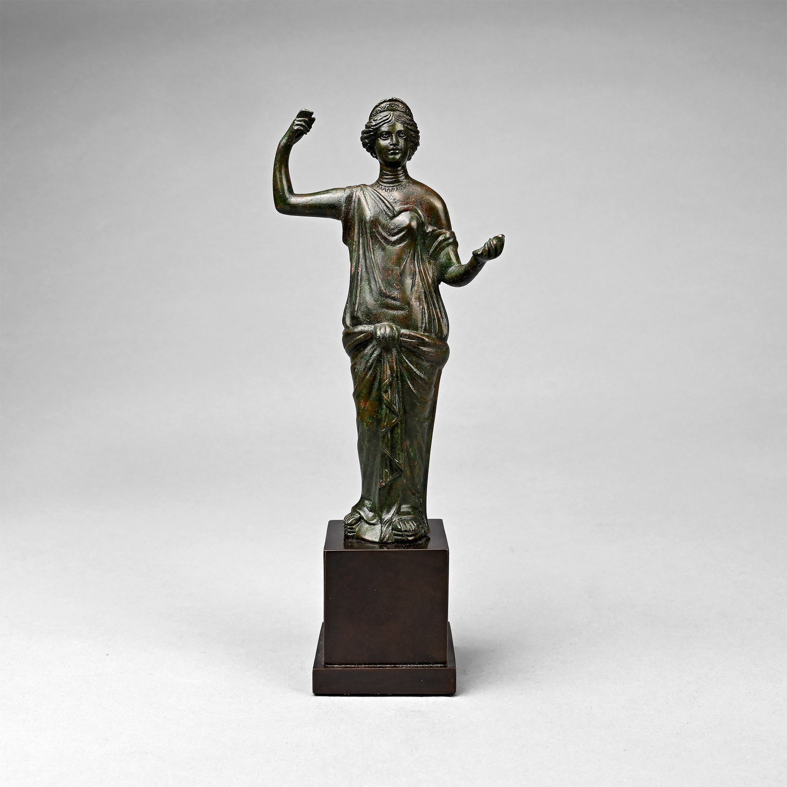 Roman Bronze Statuette of the Goddess Juno: 3rd-4th century A.D. A substantial hollow-form figure of Juno (Greek Hera) standing with right hand in gripping pose, left hand extended palm-upwards, engraved collar to the neck and diadem to the hai