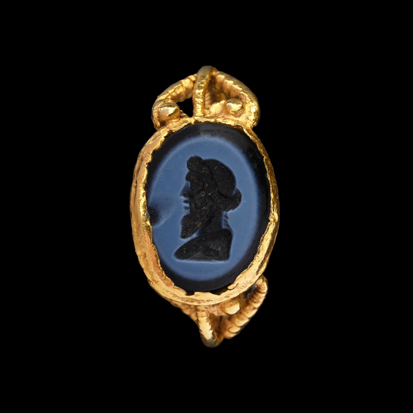 Roman Gold Ring with Nicolo Gemstone of a Bearded Bacchus as a Herm: 1st century A.D. ring: 3rd-4th century A.D. The intaglio deeply carved to depict a profile of Bacchus, set within a closed-back bezel; the band formed as a triple-twisted rope with granules and beadwo