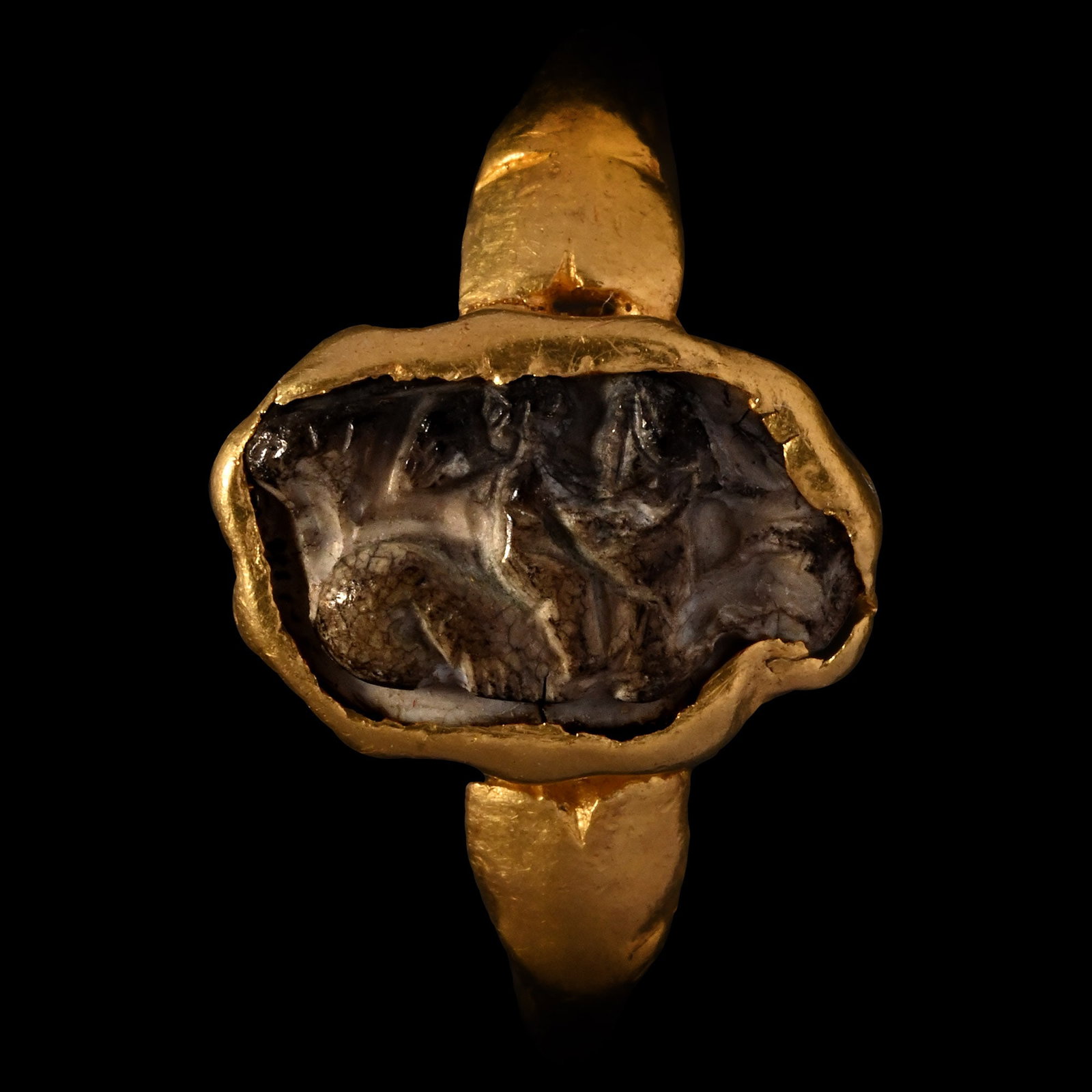 Roman Gold Ring with Burnt Agate Cameo of Eros, the Greek God of Love Riding a Hippocampus: 1st century A.D. D-section hoop with ellipsoid cell, inset cameo with Eros on a hippocamp. Cf. Chadour, A.B., Rings. The Alice and Louis Koch Collection, volume I, Leeds, 1994, item 316, for type. 3.5