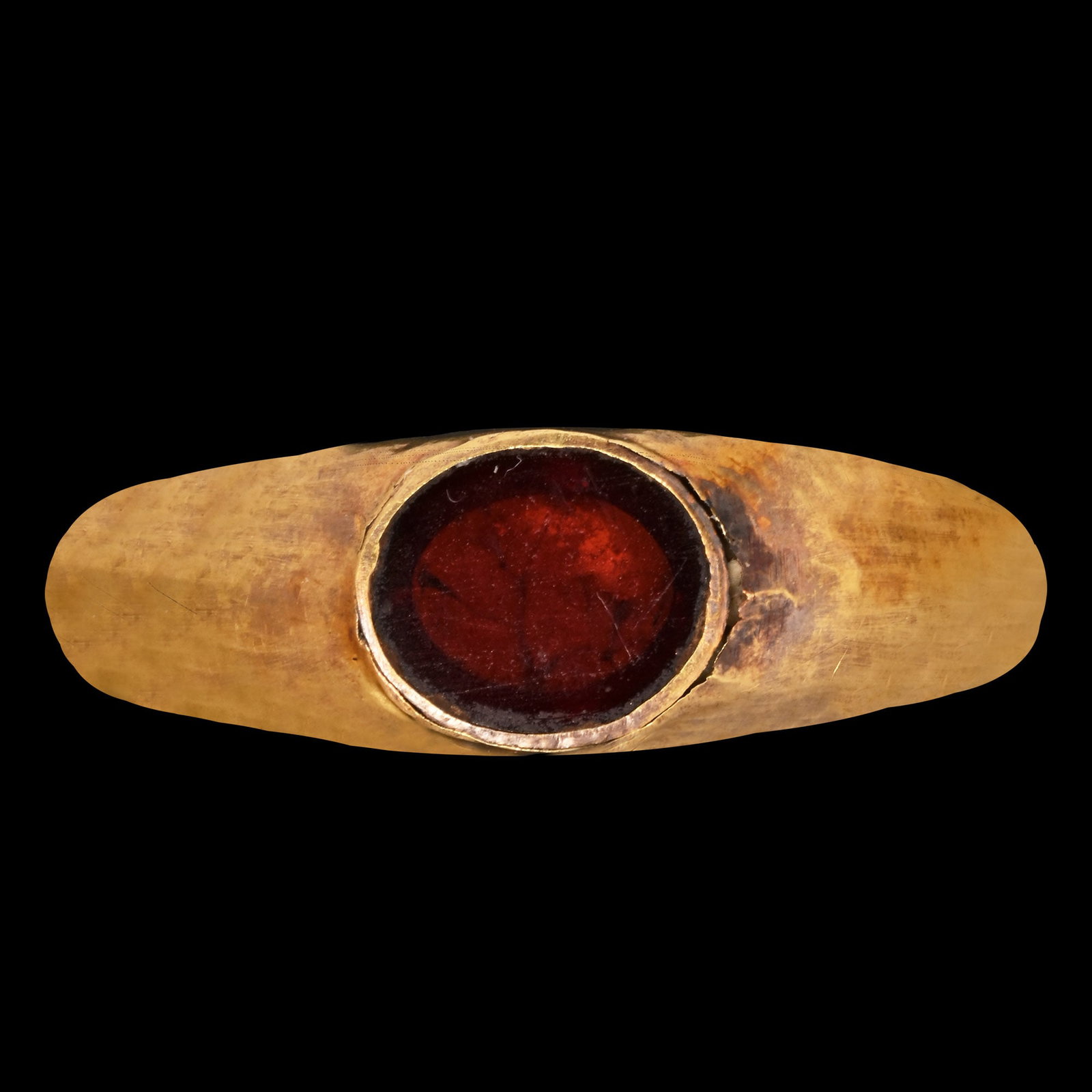 Roman Gold Ring with Red Gem: 1st century A.D. Comprising a hollow-form round-section hoop widening towards the shoulders, set with a table-cut garnet or paste with foil backing, polished. Cf. Ruseva-Slokoska, L., Roman Jewellery,