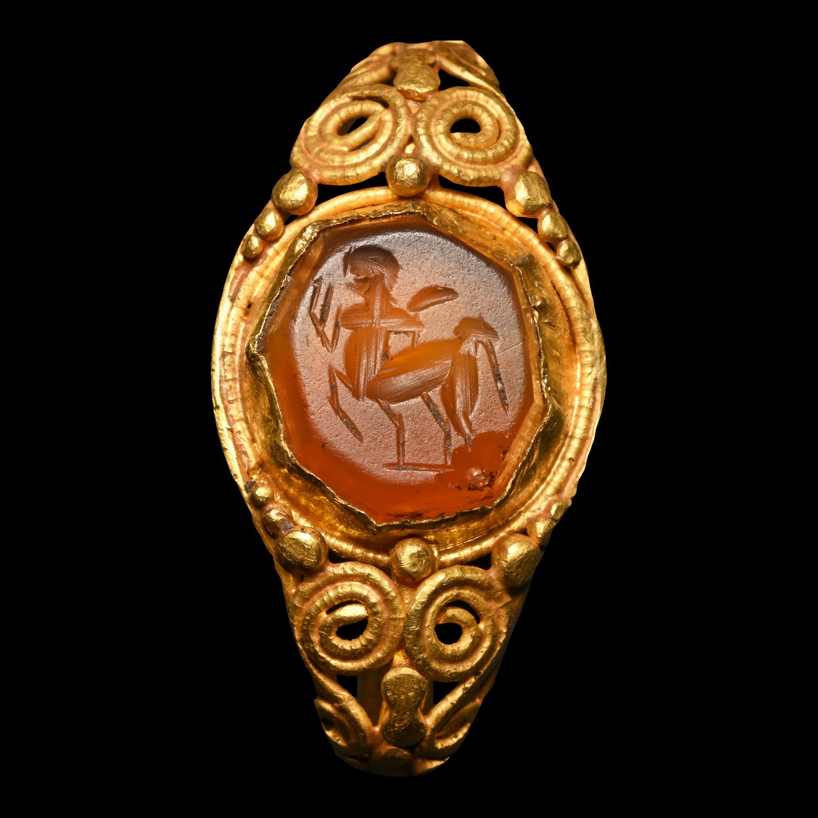 Roman Gold Ring with Carnelian Gemstone with Centaur: Late 2nd-3rd century A.D. With broad openwork shoulders and applied filigree scrolls, granulations flanking the cell with an inset facetted octagonal carnelian intaglio with an advancing centaur with 