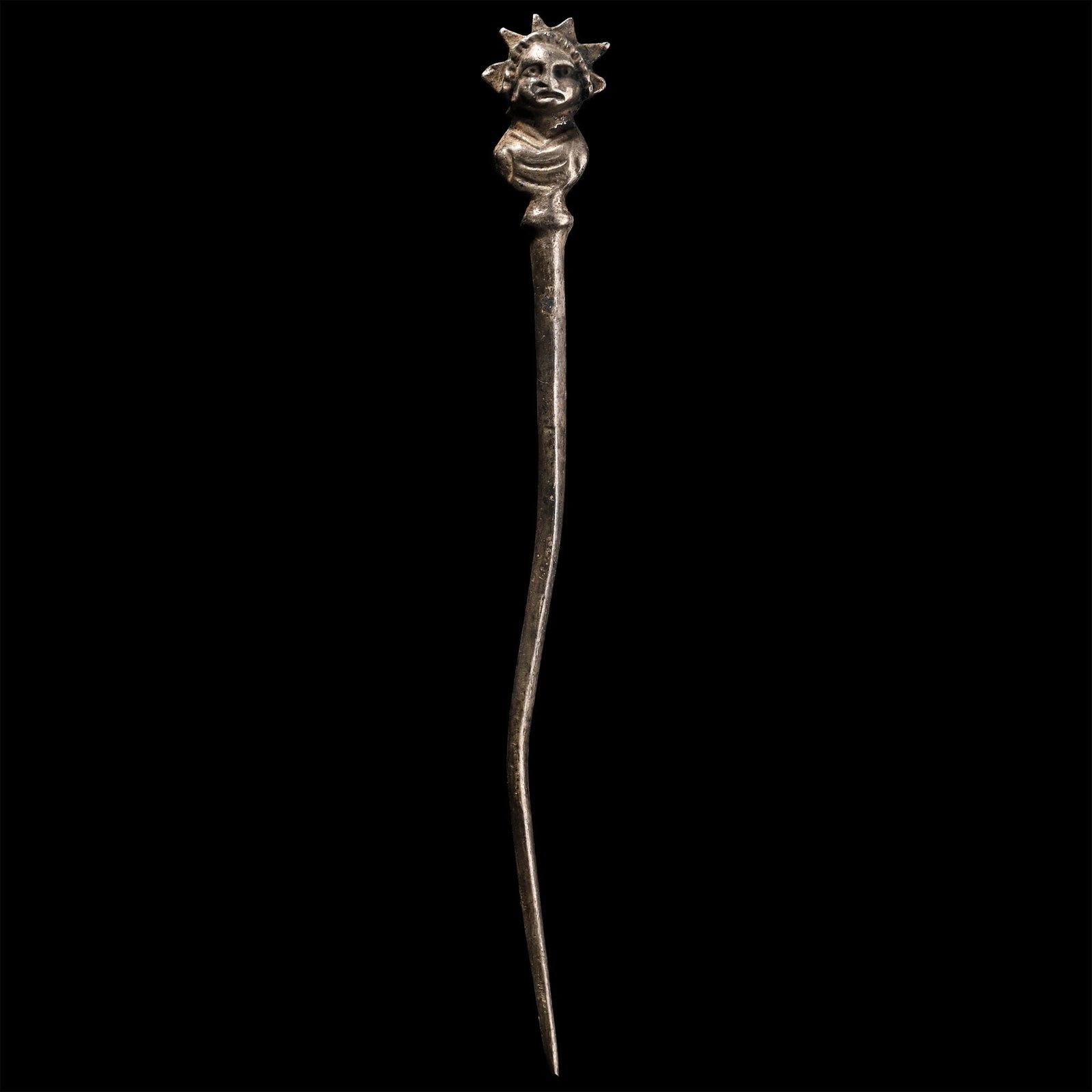 Roman Silver Pin with God Sol: 1st-4th century A.D. Comprising a tapering pin with the finial formed as the draped bust of Sol wearing a radiate crown. 9.39 grams, 10.9 cm (4 1/4 in.). Ex German art market, 2000s. Acquired from an 