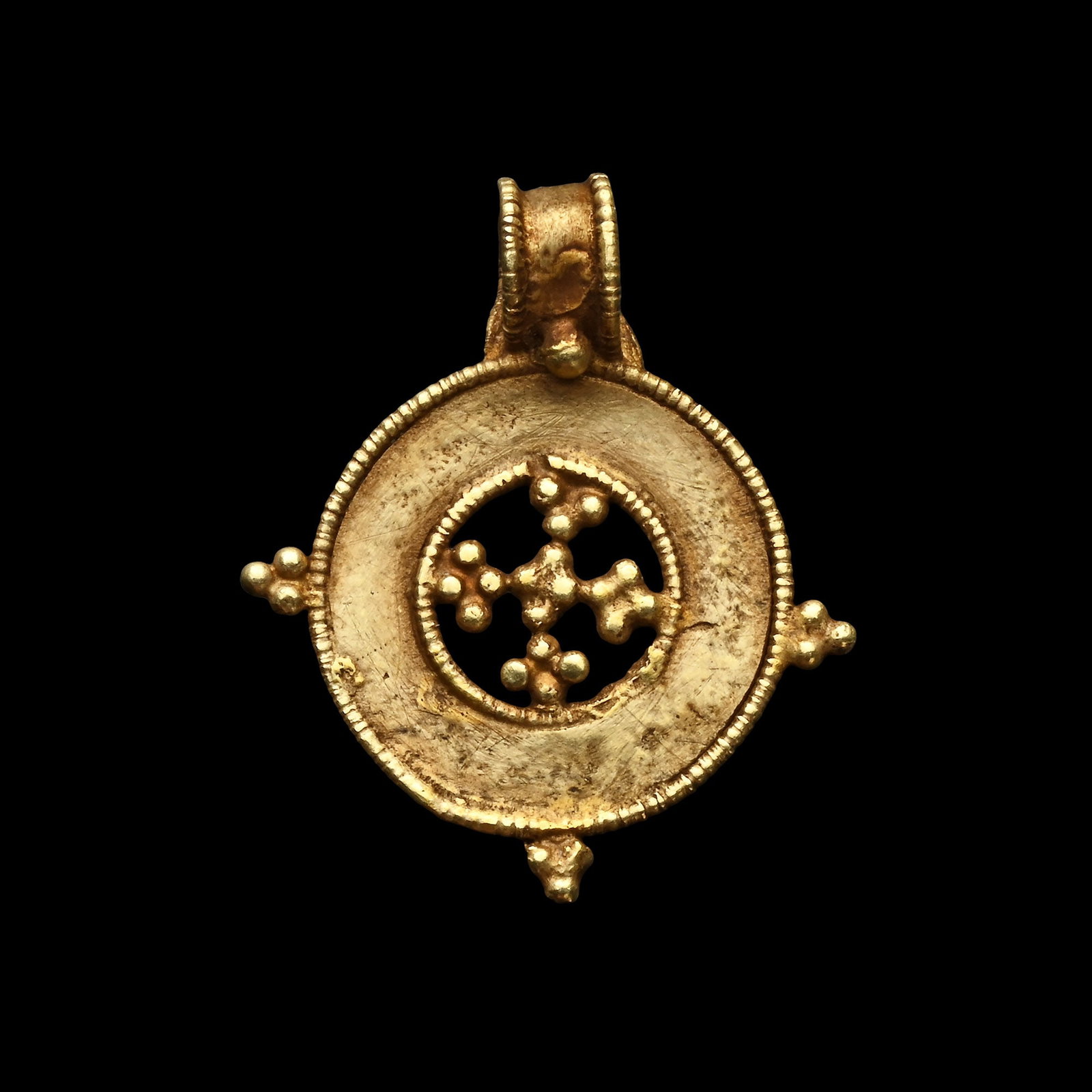 Byzantine Gold Cross Pendant: Circa 6th-8th century A.D. Comprising an annular plaque with beaded wire frame to inner and outer edges, granule clusters to three cardinal points and a cruciform cluster to the centre; a suspension l