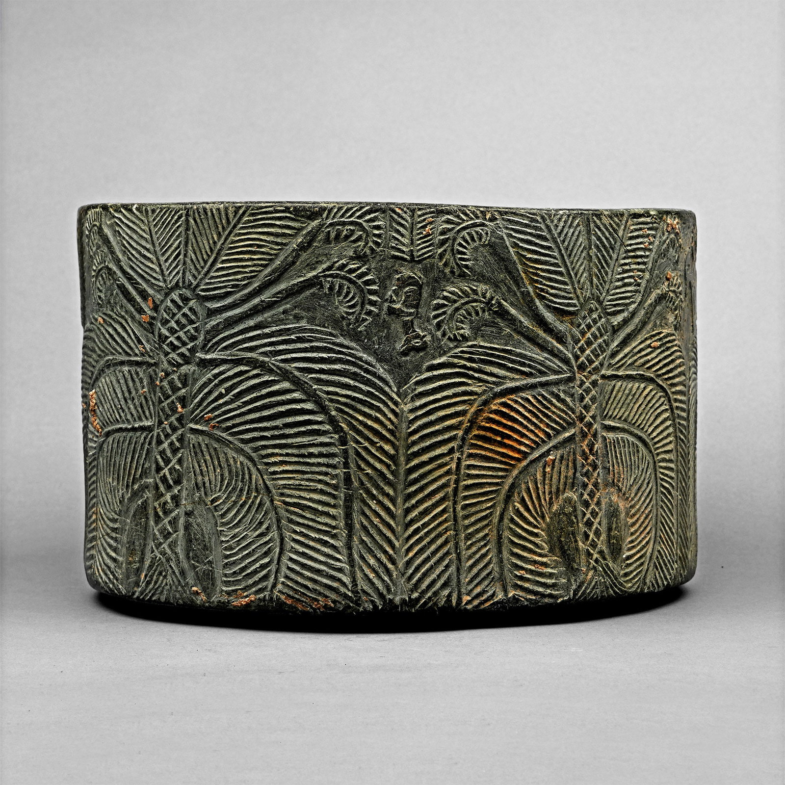 Mesopotamian Steatite Bowl with Animals and Palm Trees: 3rd millennium B.C. Drum-shaped steatite vessel with broad flat rim; low-relief frieze to the outer face: dense vegetation panels with hatched treetrunks and fronds, resting quadrupeds, each with the 