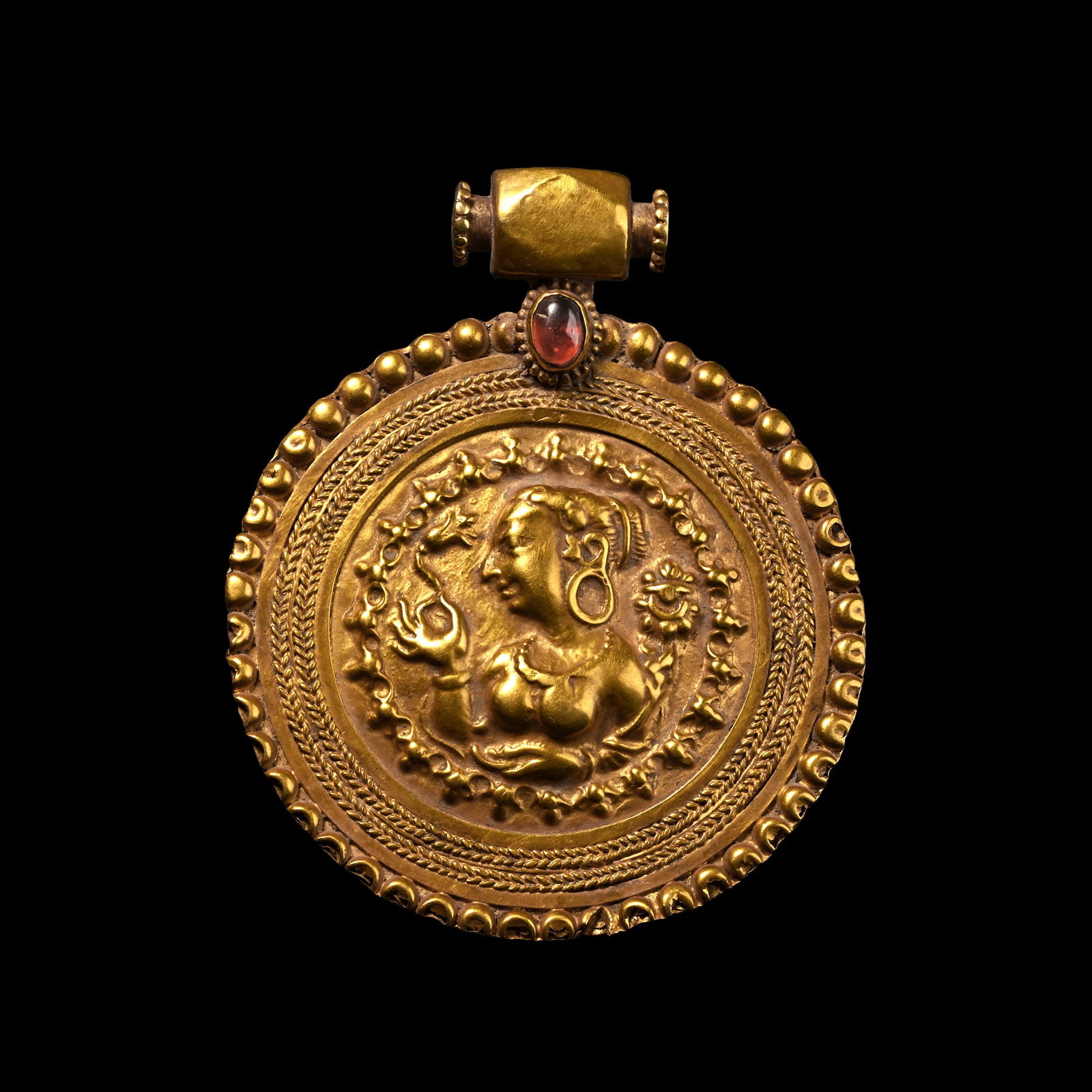 Large Kushan Gold Pendant with Bust of a Goddess: Circa 4th century A.D. A late Kushan or Hephthalites Dynasty discoid pendant with a female deity, possibly Nana, at the centre holding a lotus flower in her right hand, hair elaborately dressed and we
