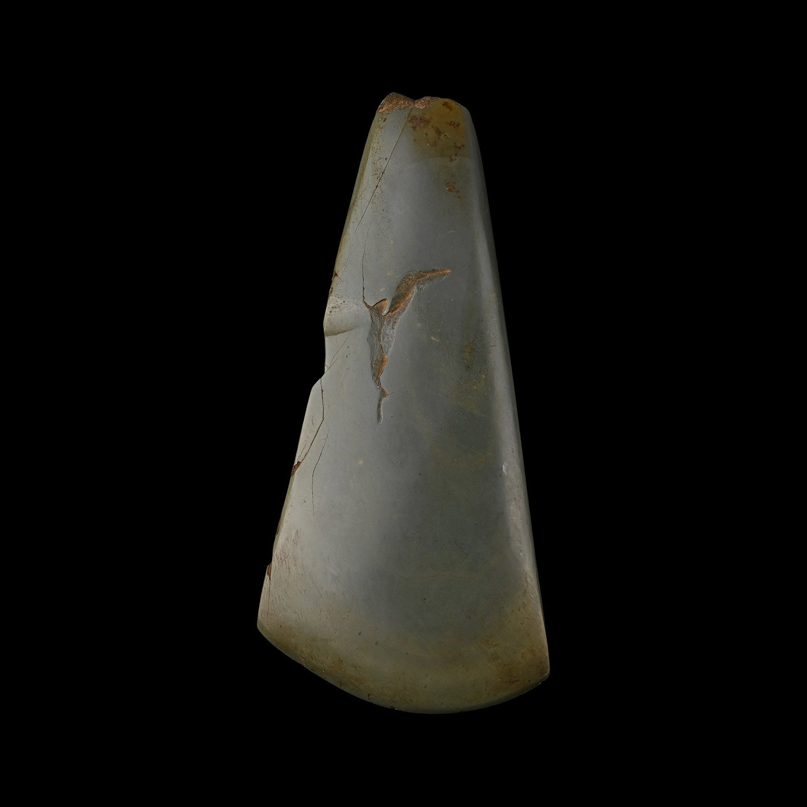 Large Greenstone Polished Axehead: Neolithic Period, circa 6th millennium B.P. Trapezoidal in form with thick butt and curved cutting edge; cracked. 1.8 kg, 29.2 cm (11 1/2 in.). Private collection, United Kingdom; reportedly found whi