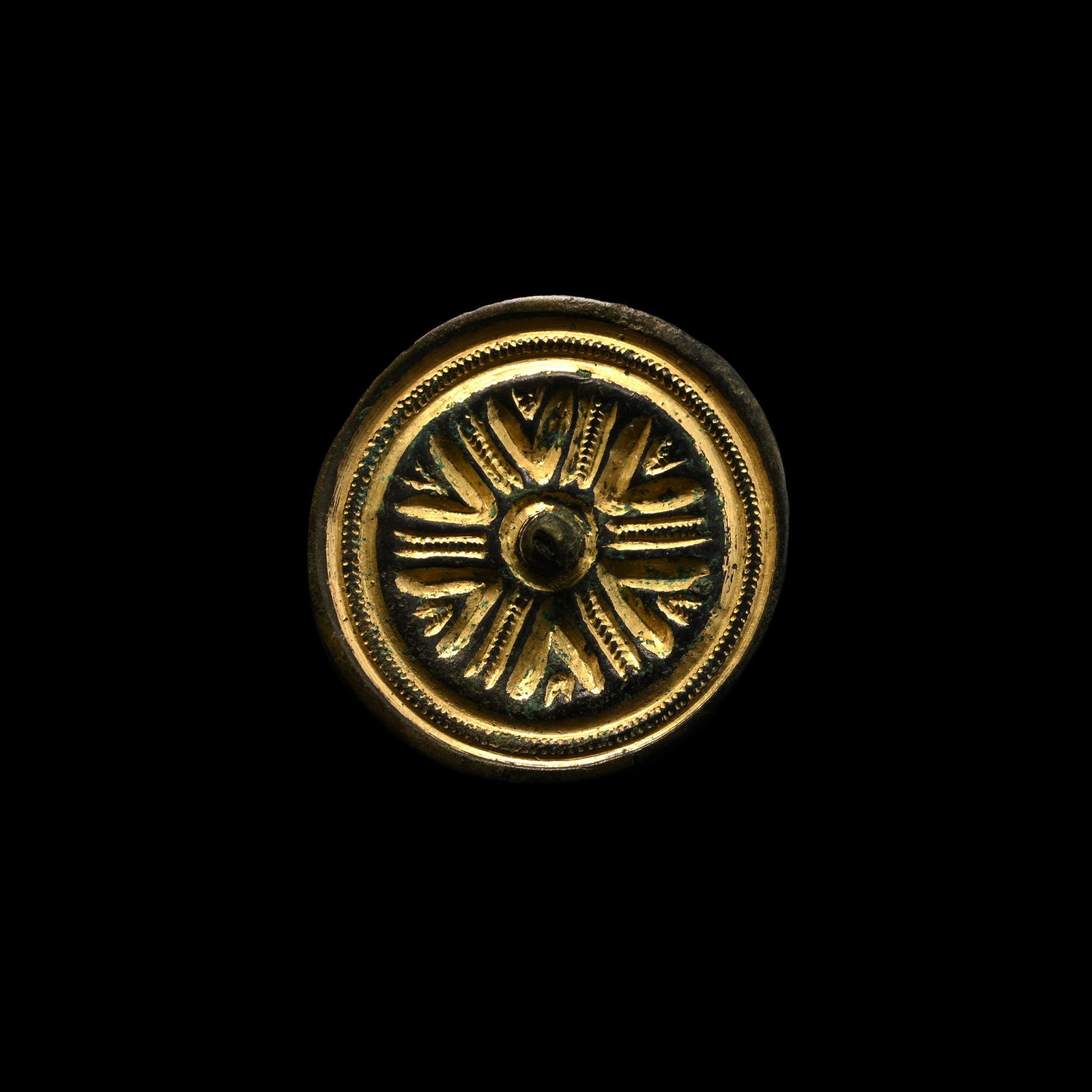 Large Anglo-Saxon Gilt Bronze Saucer Brooch: Late 5th-6th century A.D. Discoid in plan with raised rim and inner ridge decorated with notches, six radiating arms with notch detailing and interstitial chevrons; central knop rivetted from reverse;
