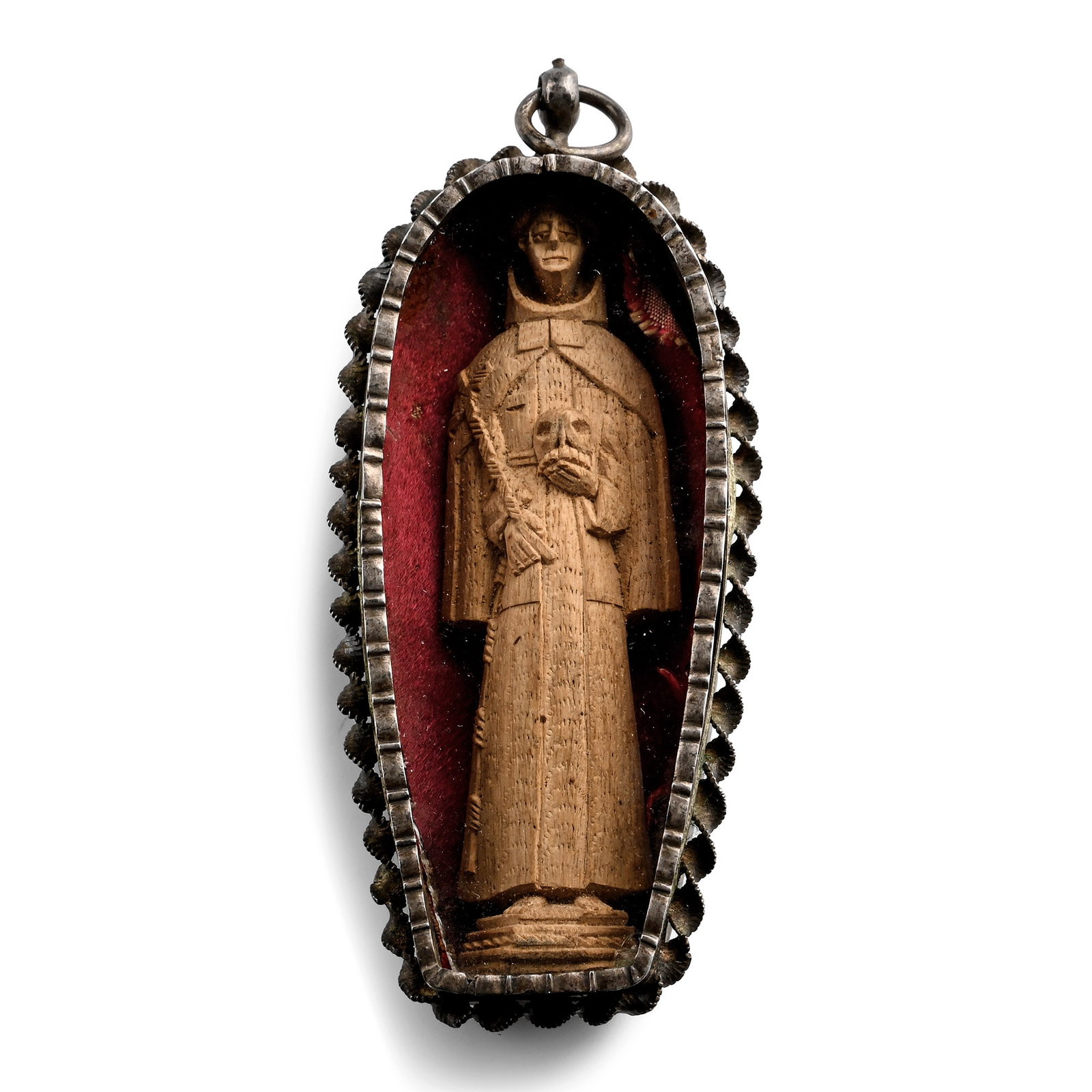 Wooden Sculpture of Saint Francis of Assisi in Silver Pendant: Spanish Colonies, 17th-18th century A.D. A carved wooden figure of Saint Francis of Assisi holding a skull in his left hand and a cross in his right hand, set on a red fabric inside a silver tongue-sh