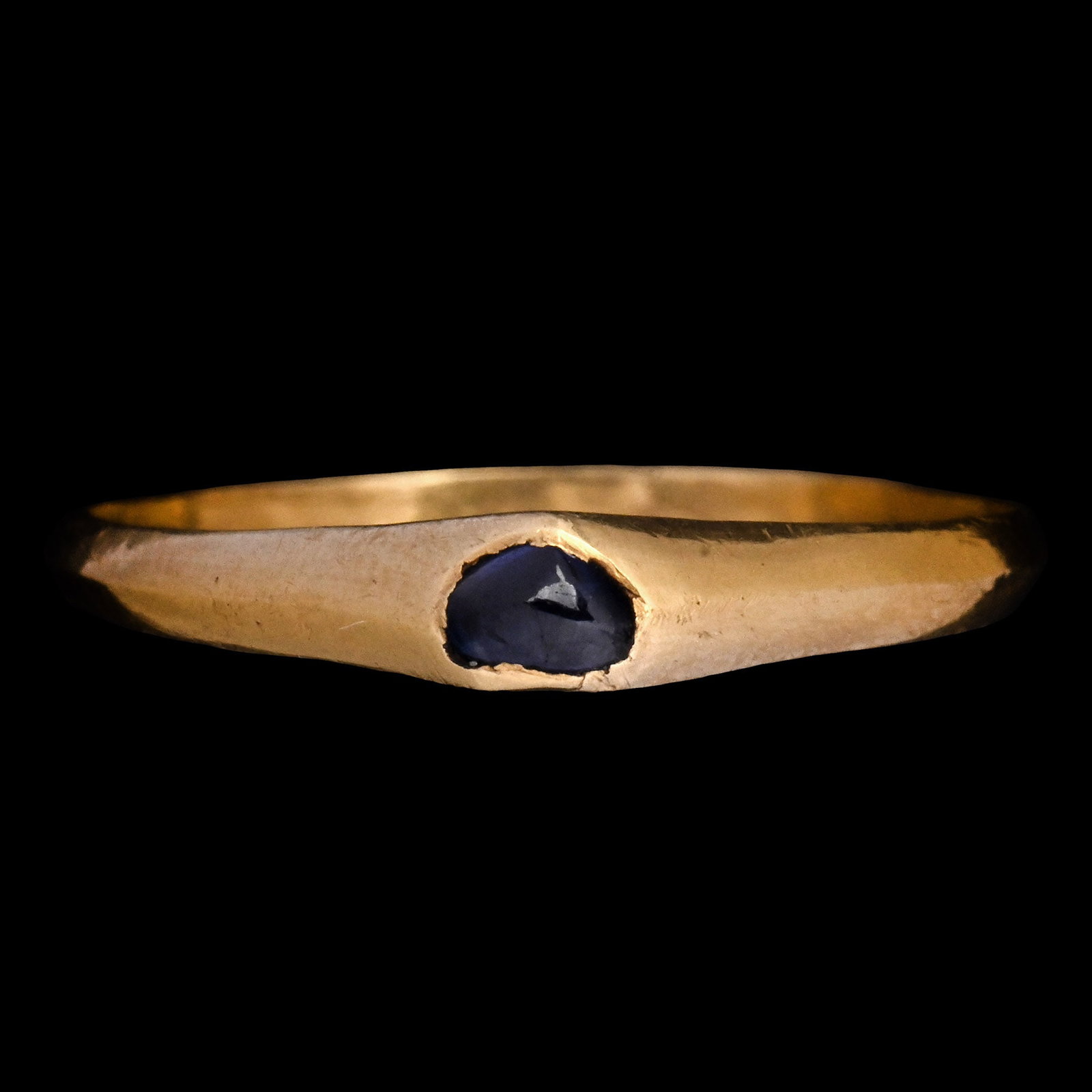 Medieval Gold Stirrup Ring with Sapphire: 13th-14th century A.D. Slender keeled hoop and a high bezel set with a polished sapphire cabochon. Cf. Chadour, A.B., Rings. The Alice and Louis Koch Collection, volume I, Leeds, 1994, item 565, for a