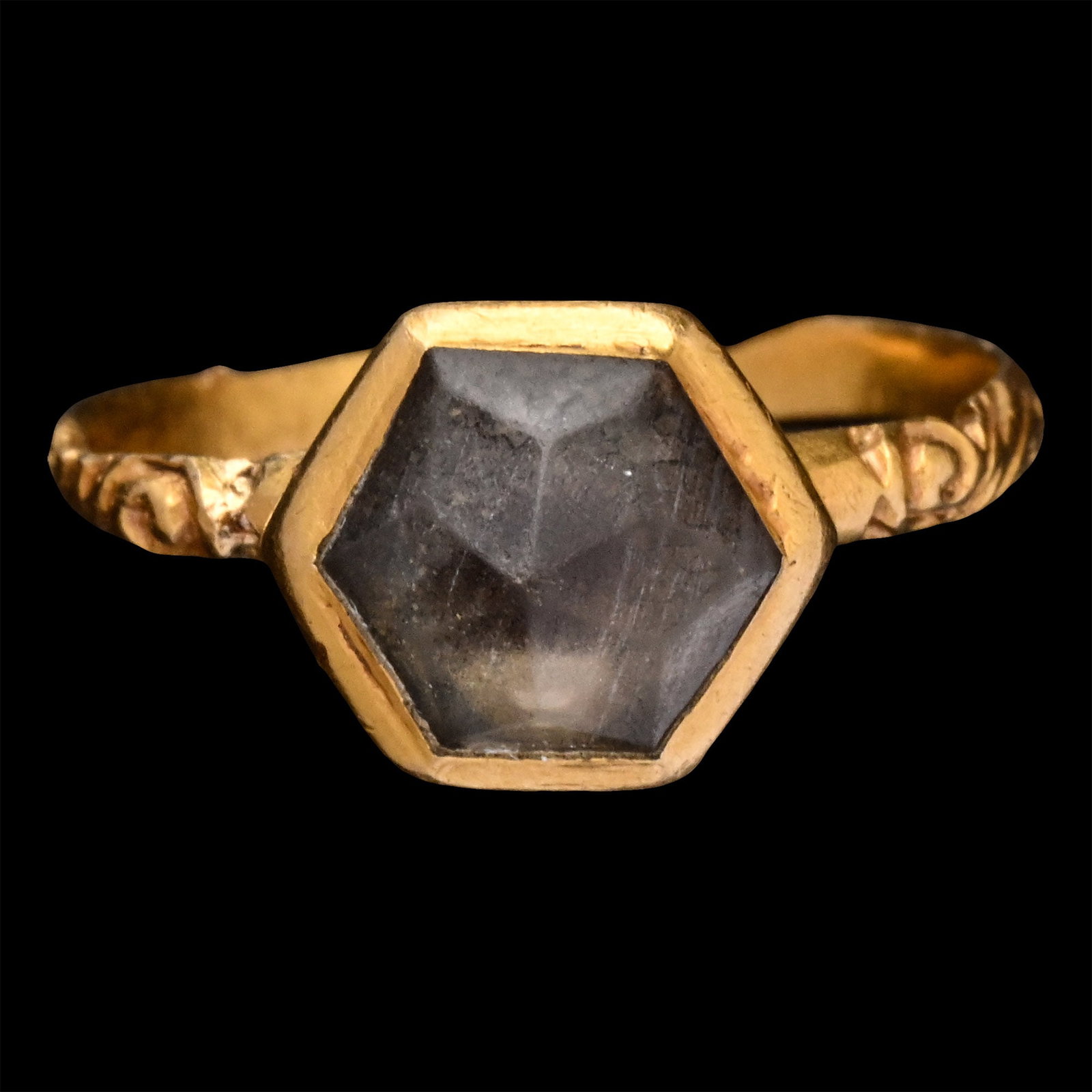 Renaissance Gold Ring with Gem: 16th century A.D. Comprising a slender hoop with scroll-decorated shoulders, a high hexagonal colette setting with a point-cut rock crystal with foil backing. 2.75 grams, 22.97 mm overall, 15.54 mm in