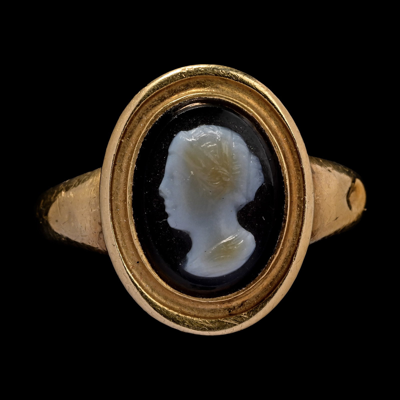 Post Medieval Banded Agate Cameo of a Woman in Gold Ring: 18th century A.D. Hollow-formed with pie-dish bezel and inset cameo. Cf. Chadour, A.B., Rings. The Alice and Louis Koch Collection, volume I, Leeds, 1994, item 790, for type. 3.17 grams, 21.26 mm over