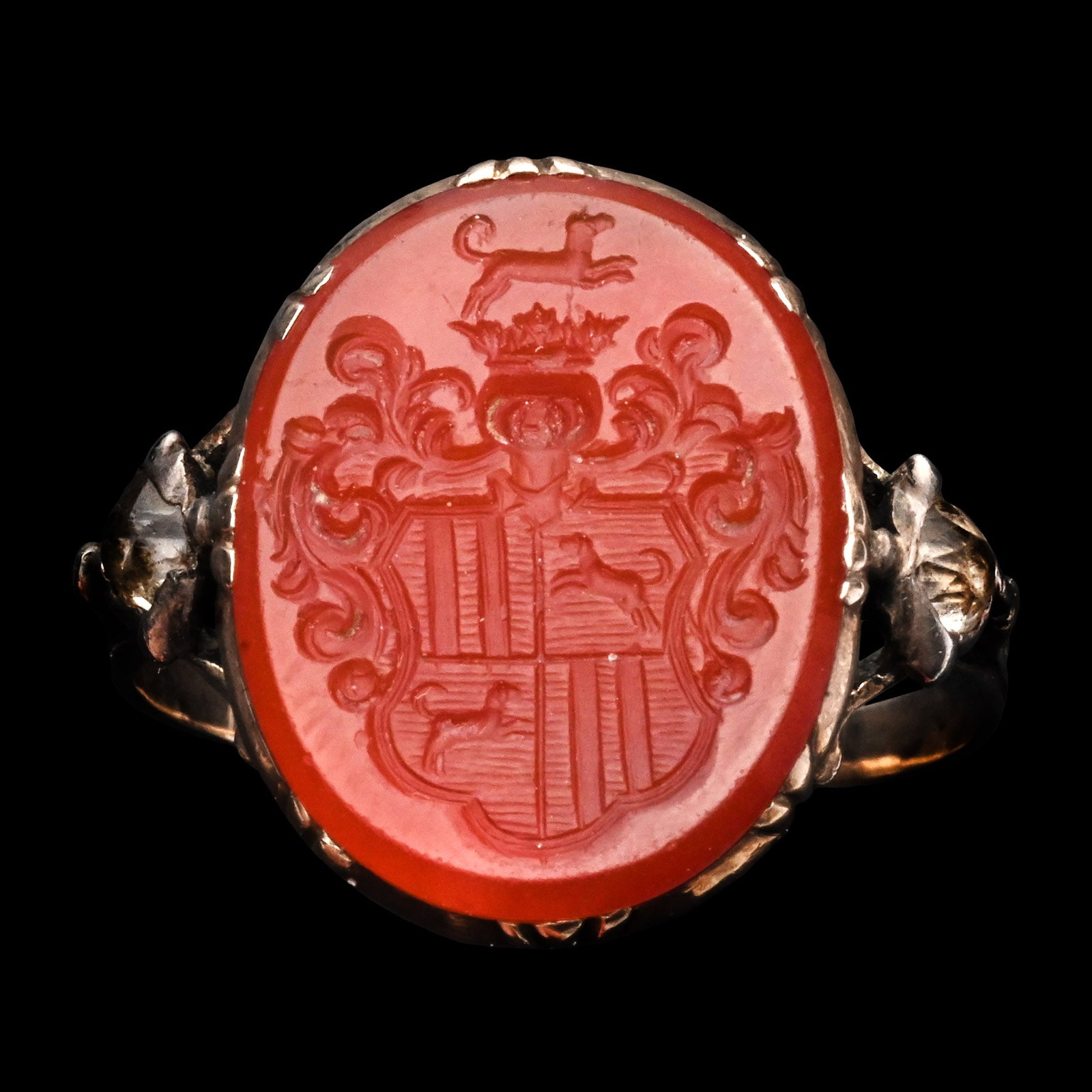 Holy Roman Empire Gold Signet Ring with Carnelian Intaglio: Germany, 18th century A.D. Comprising a fluted band with openwork shoulders set with facetted rock crystals, rub-over setting engraved with floral motifs on the reverse and set with a red carnelian in