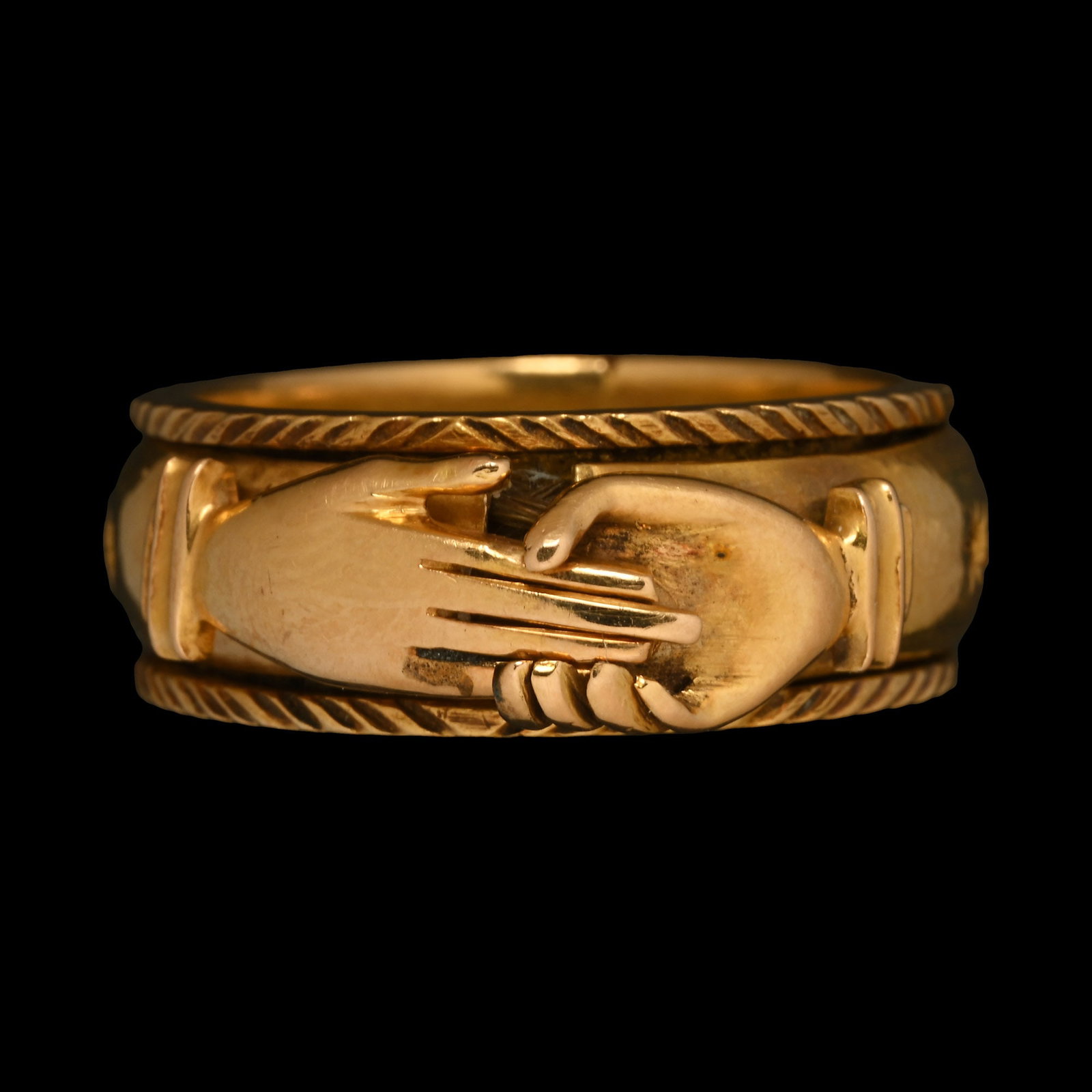 Georgian Gold Mourning Ring with Opening Clasped Hands: Dated 14th December 1774 A.D. Formed of a wide band with faux-ropework borders and plaited brown hair, hinged outer cover with the locking mechanism formed as two clasping hands, three circular openin
