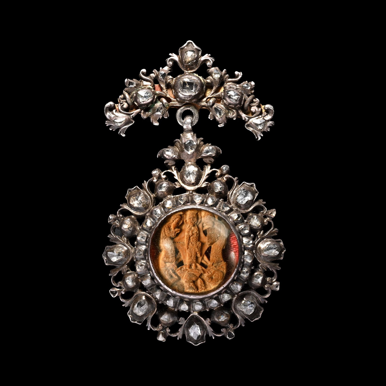 Silver and Diamond Pendant with Holy Trinity: Spain, circa 1700 A.D. The elaborate openwork pendant set with old-cut diamonds, the hanger centred with a table-cut diamond; at the centre a circular glazed compartment containing a Greek Orthodox, m