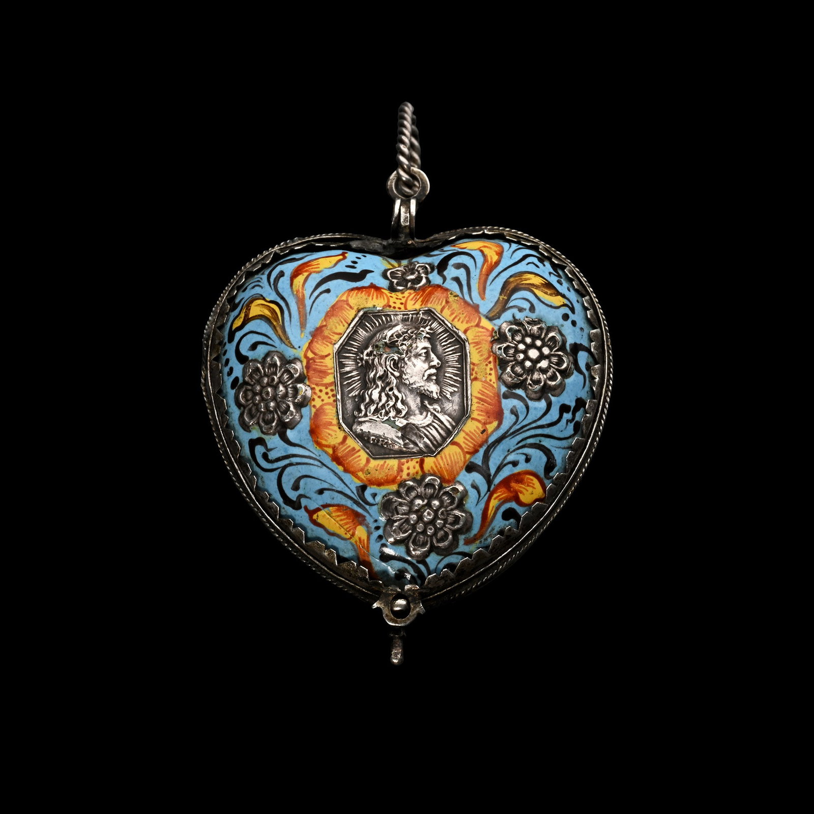 Enamelled Pendant in the form of a Heart with Silver Decorations: Germany, 17th century A.D. Hinged pendant decorated in blue, yellow and red enamel with silver floral decoration, one side with a silver profile of the Virgin, and the other side with the profile of C