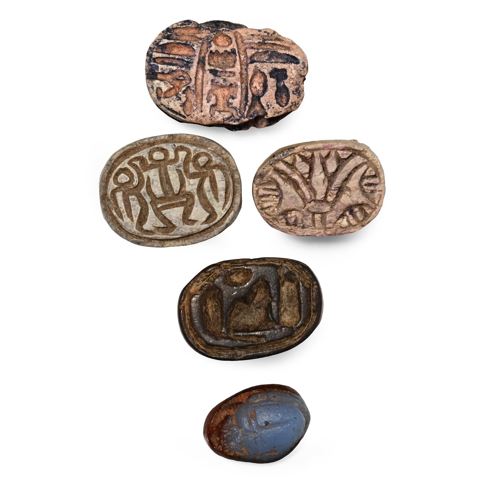 Egyptian Stone and Faience Scarab Group: 2nd-1st millennium B.C. Comprising: a blue glazed scarab with the cartouche of Thutmosis III (Men-kheper-Ra) on the underside flanked by other signs; a scarab with three schematic human figures; a sca