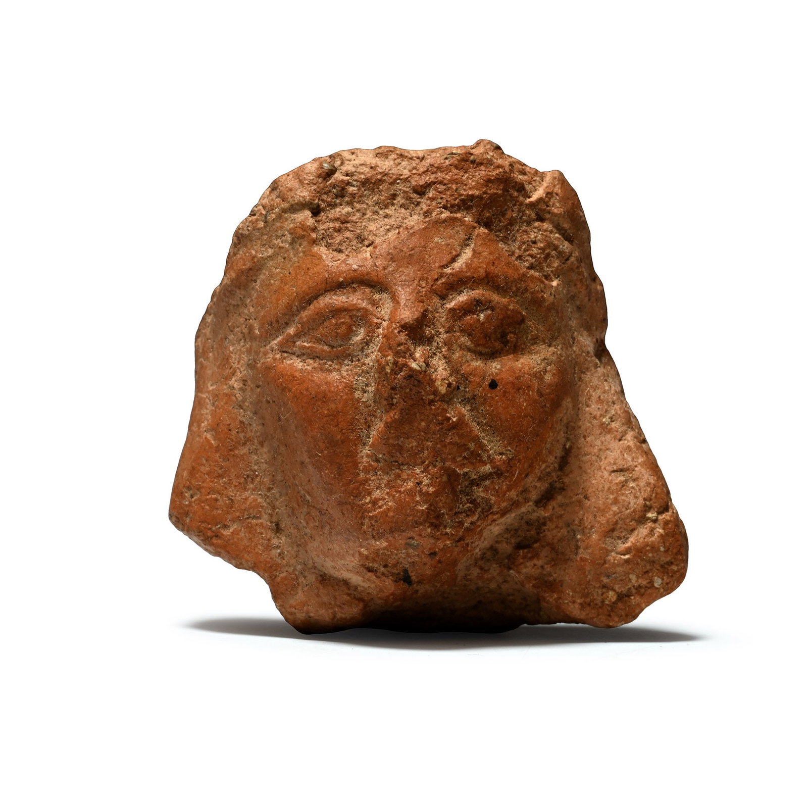 Phoenician Terracotta Head: 6th-5th century B.C. Tongue-shaped fragment depicting a figure with almond-shaped eyes and wearing a headdress. Cf. Moscati, S., I Fenici Milano, 1988, p.150, for a similar statuette from Amrit. 65 gr