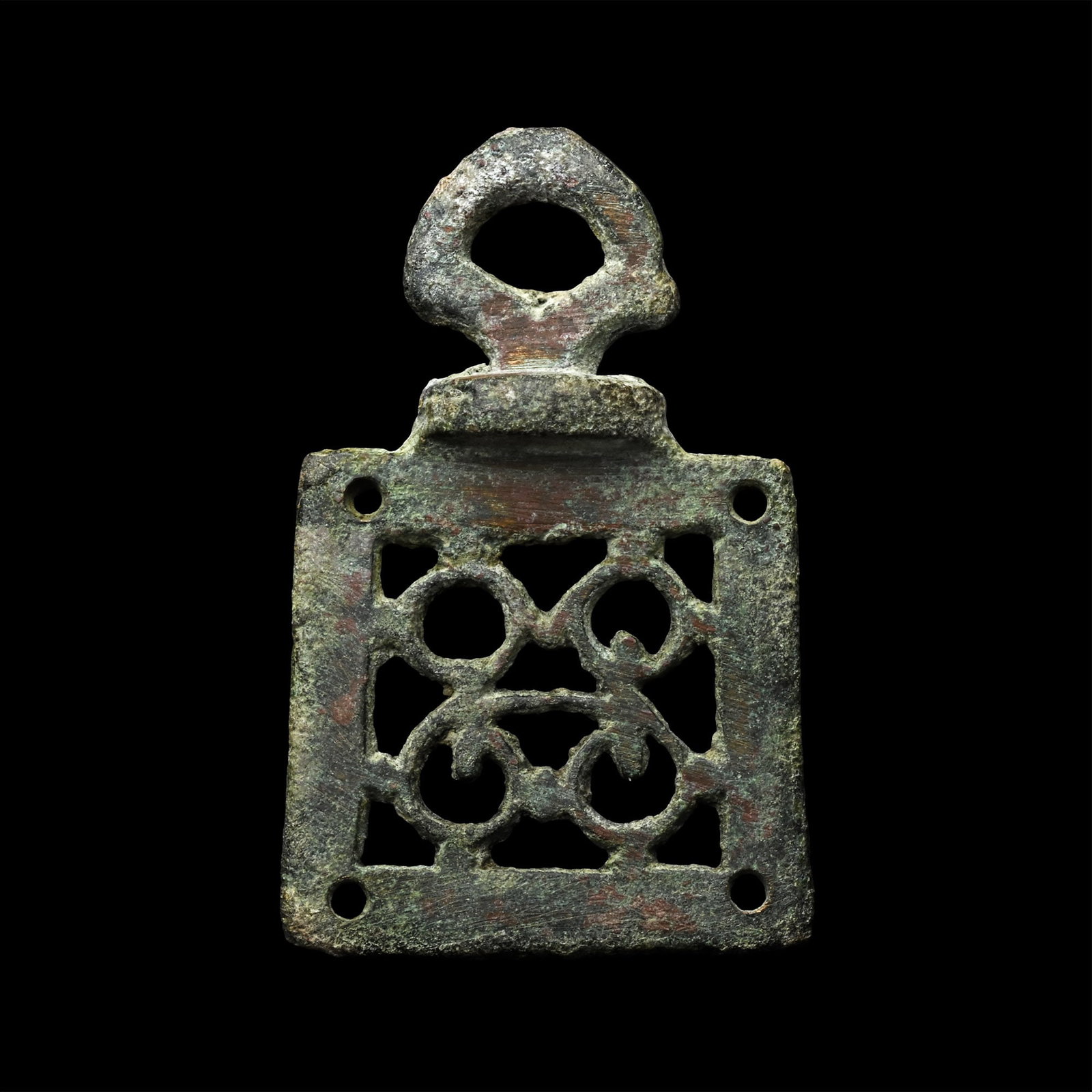 Roman Bronze Openwork Mount: Circa 1st-2nd century A.D. Trapezoidal plaque with openwork scroll detailing, pierced at each corner for attachment, voided tab at the lower edge. 8.78 grams, 41 mm (1 5/8 in.). [No Reserve] Acquired 