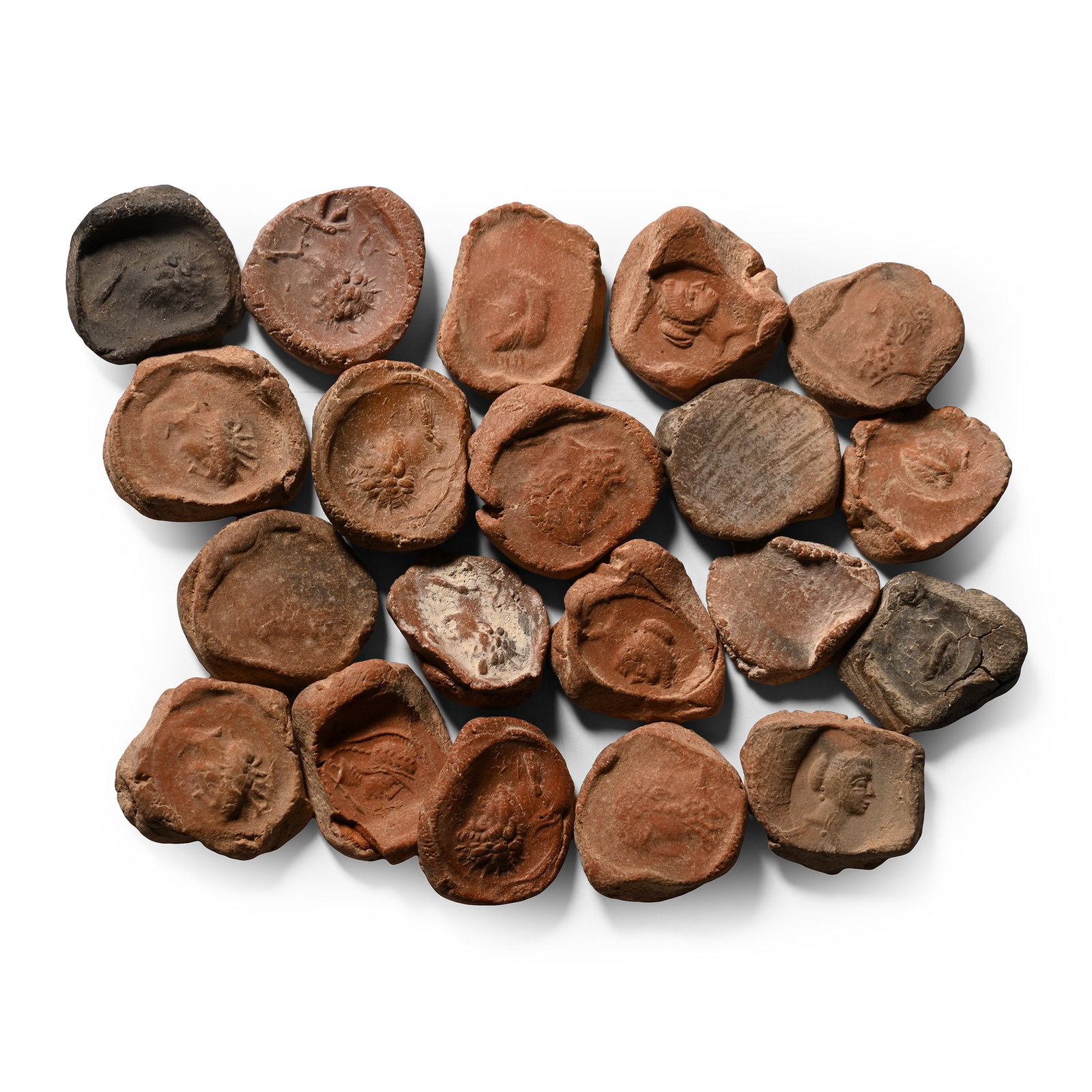 Roman Terracotta Bullae, Tesserae or Token Group: 3rd century B.C.-1st century A.D. A mixed group of ceramic bullae, tesserae or theatre tokens bearing low-relief motifs, mainly consisting of profile busts of deities. 37.4 grams total, 17-20 mm (5/8 