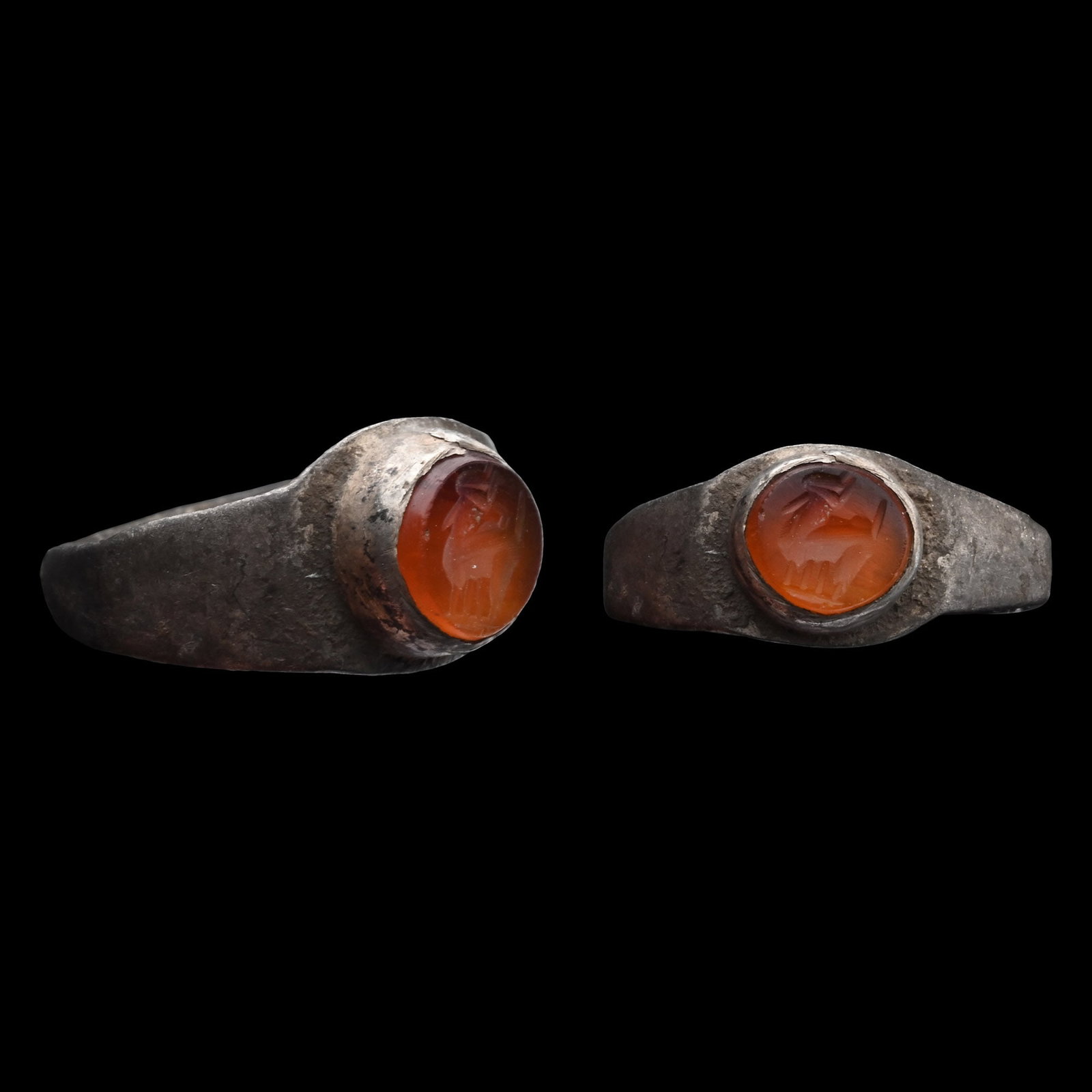 Roman Silver Ring with Carnelian Animal Gemstone: Circa 2nd-3rd century A.D. With wide shoulders and a rub-over bezel set with an orange carnelian intaglio engraved with a standing horned quadruped, possibly a goat. 3.27 grams, 22.88 mm overall, 19.4