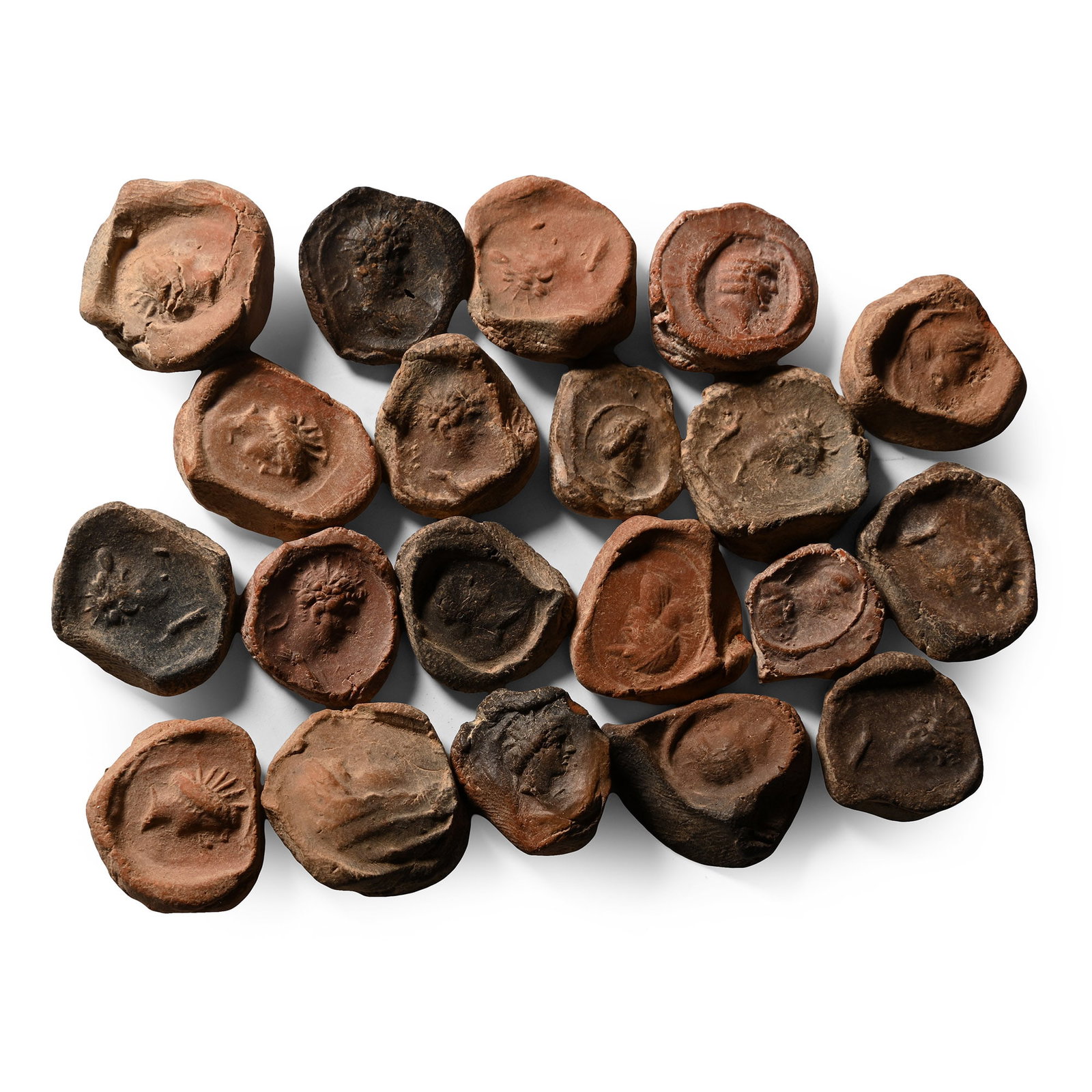 Roman Terracotta Bullae, Tesserae or Token Group: 3rd century B.C.-1st century A.D. A mixed group of ceramic bullae, tesserae or theatre tokens bearing low-relief motifs, mainly consisting of profile busts of deities. 38.8 grams total, 15-22 mm (5/8 