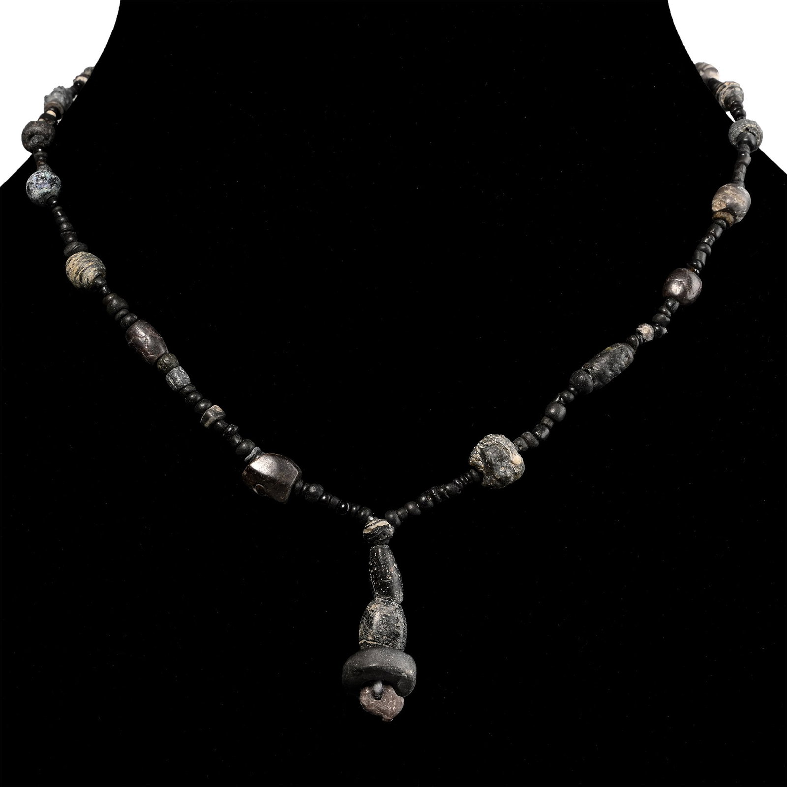Roman Black Glass and Other Bead Necklace String: 1st-4th century A.D. and later. Composed of small beads interspersed with larger oblate and other beads, the central feature composed of larger beads; restrung. 9.8 grams, 33 cm (13 in.). [No Reserve]