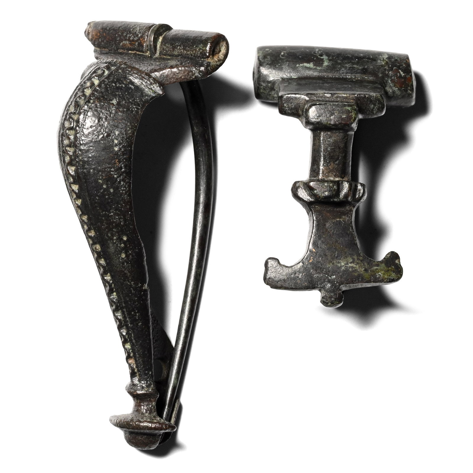 Roman Bronze Brooch Group: 1st-4th century A.D. Comprising a dolphin brooch with a decorative wave motif, and a bow brooch with a flaring foot. 29.4 grams total, 35-55 mm (1 3/8 - 2 1/8 in.). [2] Ex German art market, 2000s. Ac