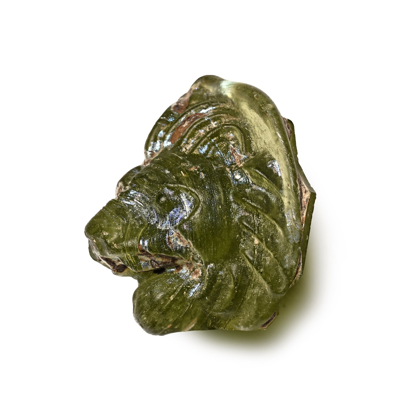 Large Roman Glass Roundel with Lion: 3rd-4th century A.D. Pale green roundel showing a lion's head in three-quarter view, the beast with open jaws and voluminous mane. Cf. similar heads in Kucharczyk, R., ?Glass medallion in the shape of