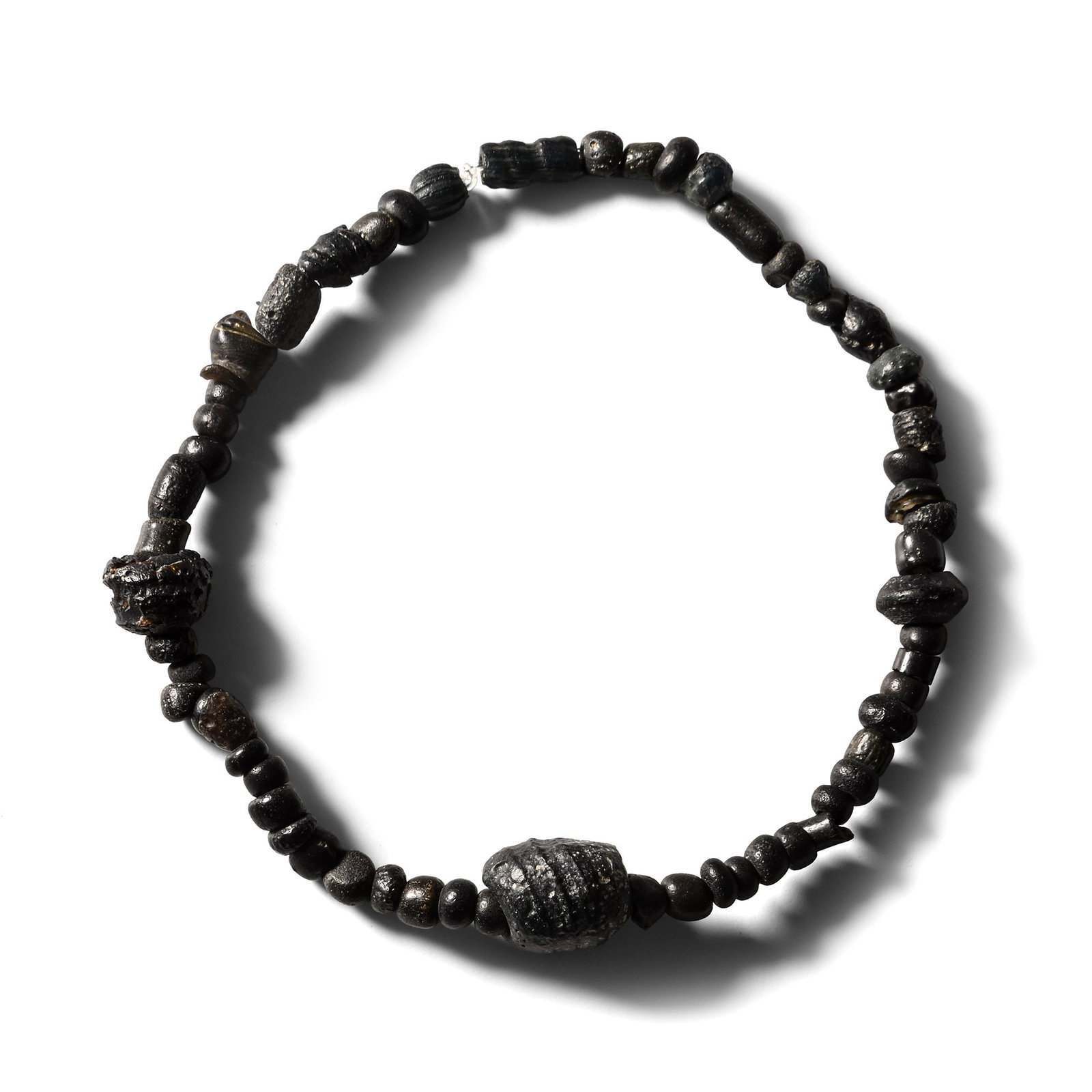 Roman Black Glass Bead Bracelet: 1st-4th century A.D. and later. Composed mainly of oblate beads with a larger feature bead, restrung with an elasticated string. 4.41 grams, 17 cm (6 3/4 in.). [No Reserve] Ex Ancient Art Shop, Windso