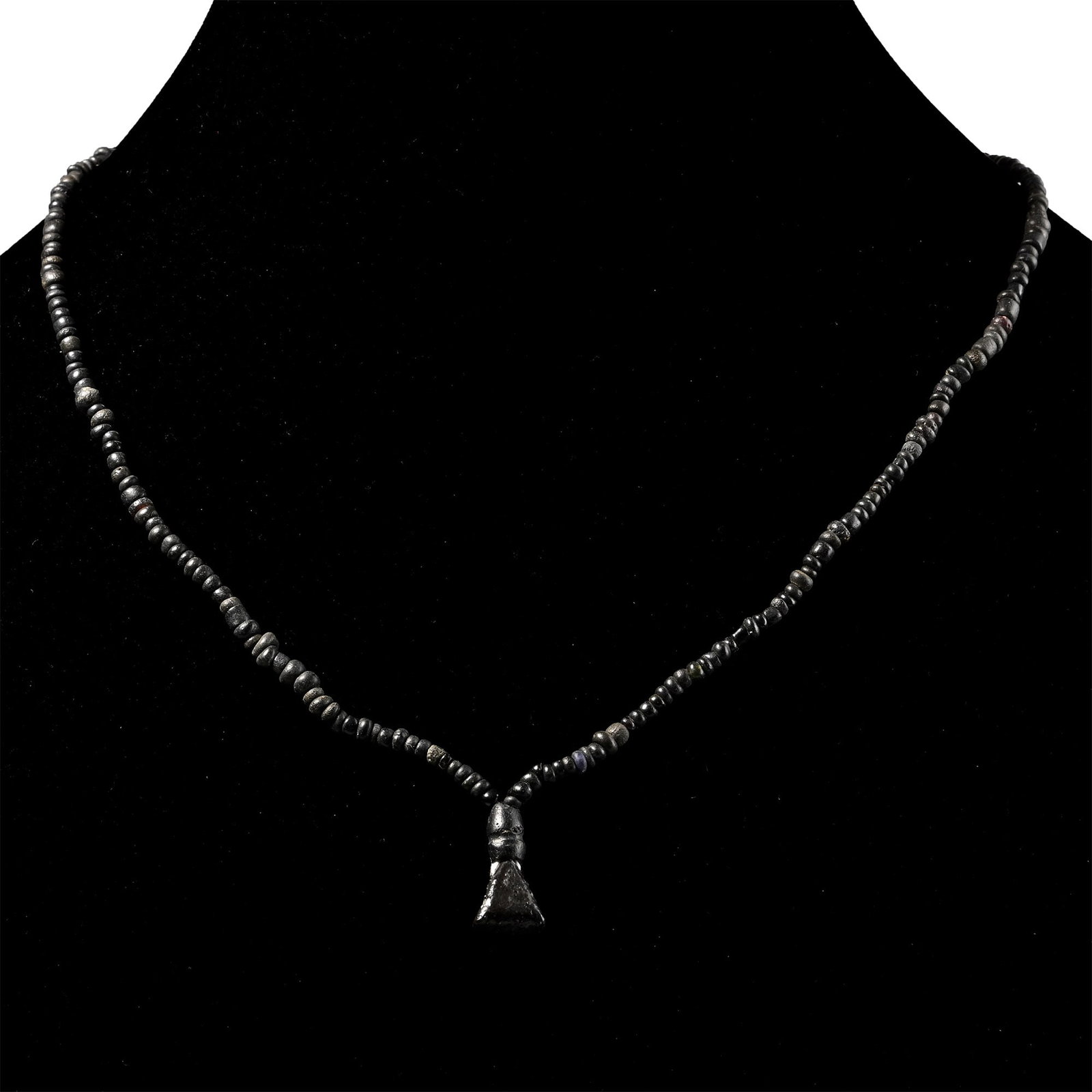 Roman Black Glass and Other Bead Necklace String: 1st-4th century A.D. and later. Mainly composed of oblate and annular beads, the central feature with a tabular triangular bead; restrung. 7.5 grams, 44.5 cm (17 1/2 in.). [No Reserve] Acquired in the