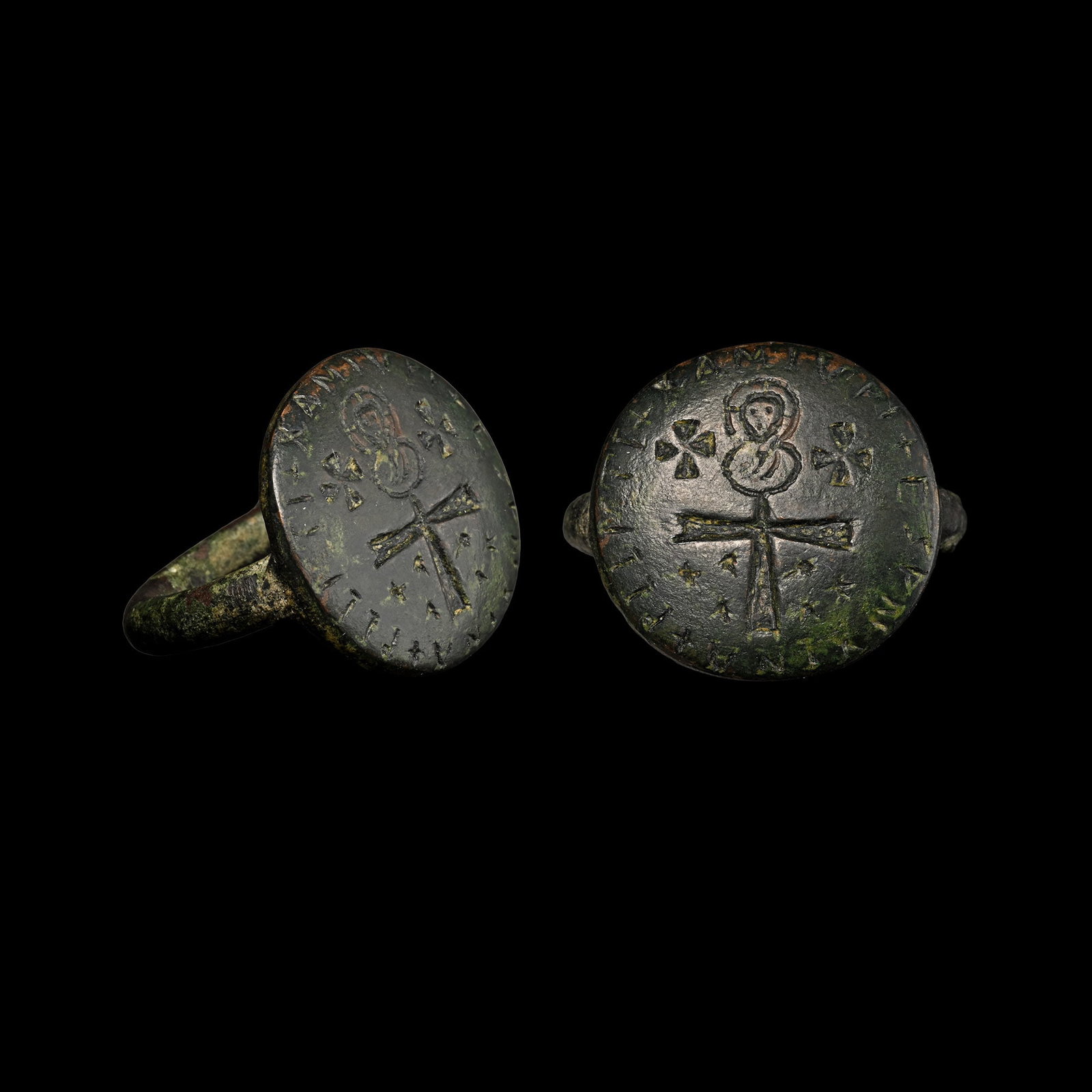 Large Byzantine Bronze Ring with Cross and Saint: Circa 6th-7th century A.D. Comprising a thick round-section hoop and integral disc bezel; incuse cross with nimbate bust above flanked by two equal-arm crosses, enigmatic legend to the rim. 18.62 gram