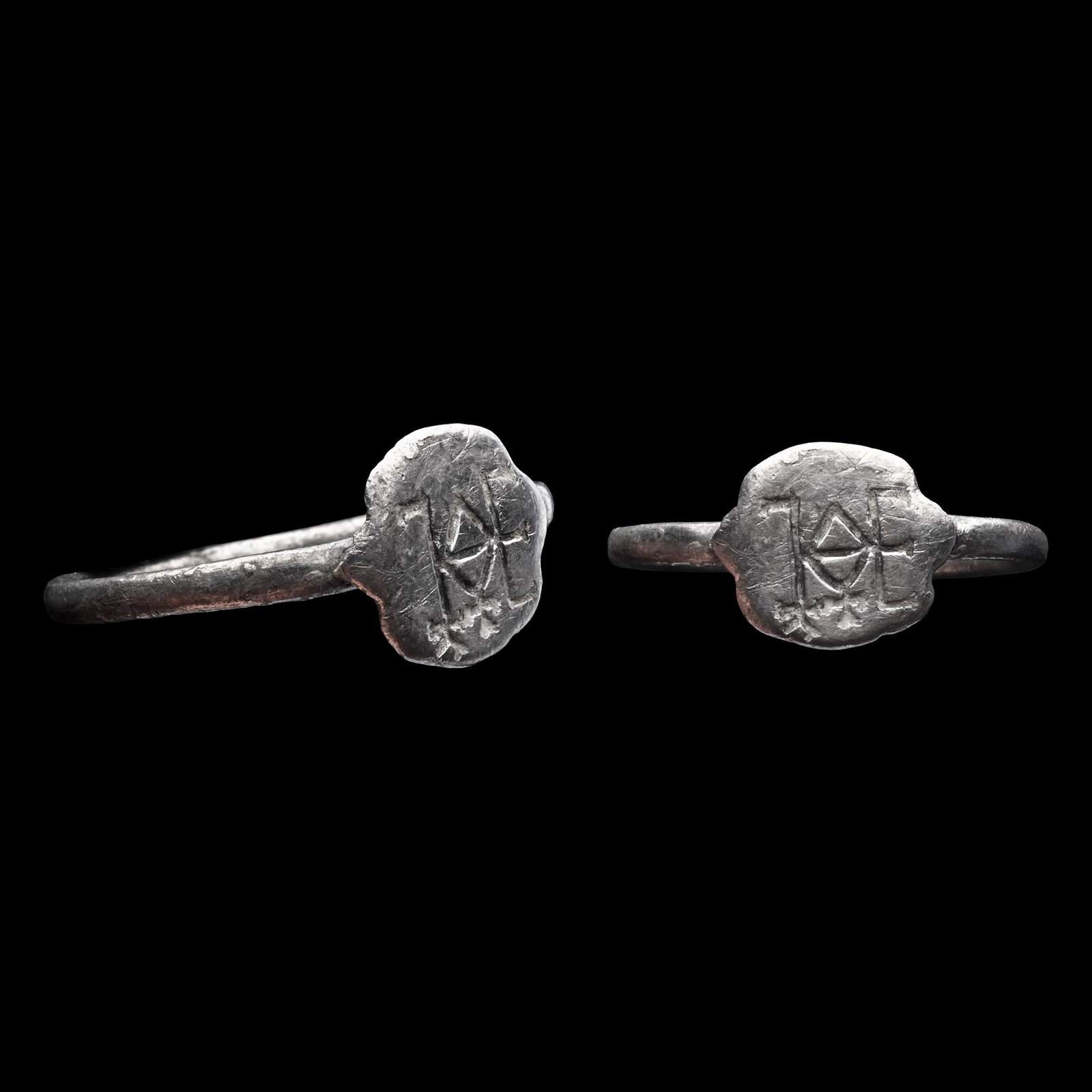 Byzantine Silver Ring with Monogram: Circa 6th-7th century A.D. Comprising a round-section hoop with an applied discoid bezel bearing a monogram. 2.39 grams, 21.45 mm overall, 17.95 mm internal diameter (approximate size British N 1/2, U