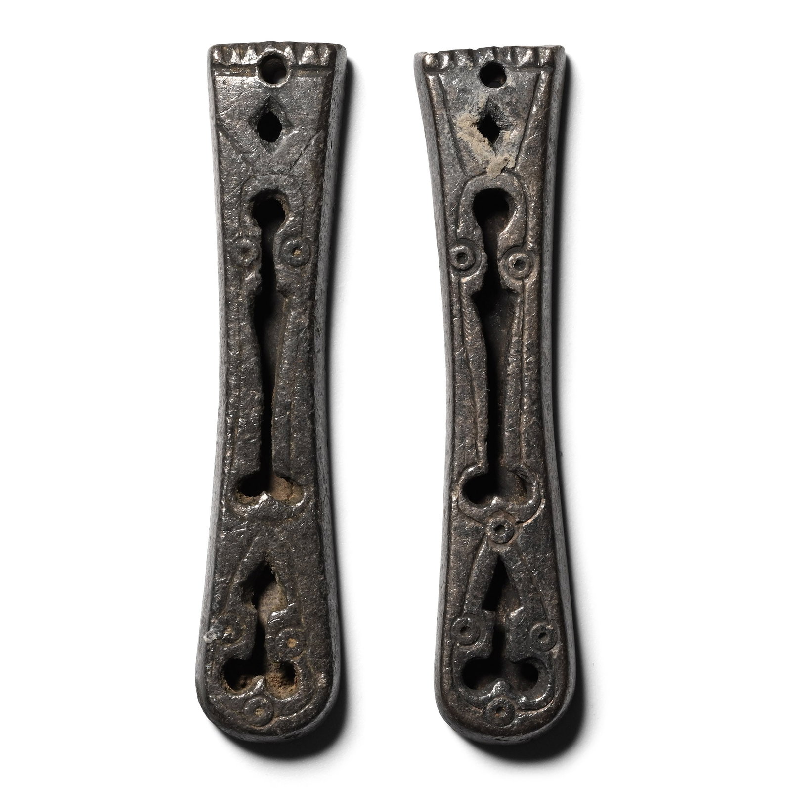 Byzantine Silver Strap End Group: Circa 6th-7th century A.D. Matching pair of strap ends with openwork decoration on the tongue-shaped body. 9.76 grams total, 44 mm each (1 3/4 in.). [2] Acquired on the UK art market before 2000. From