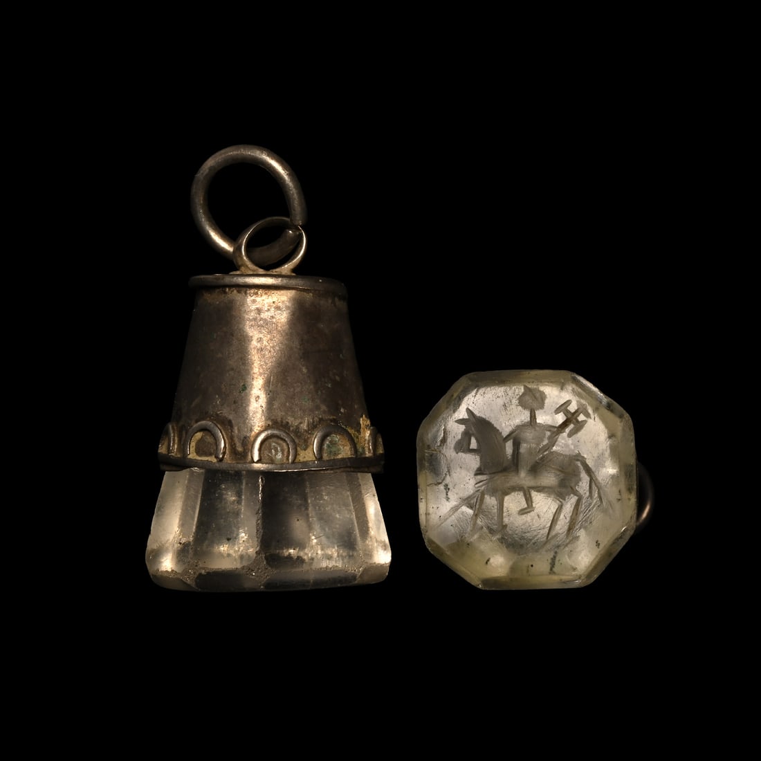 Byzantine Rock Crystal Stamp Seal in Silver Pendant with Military Saint on Horseback: Circa 6th-7th century A.D. With a tapering octagonal body, the military saint on horseback holding a long spear, the horse wearing a detailed harness; set in a conical silver frame with suspension loo