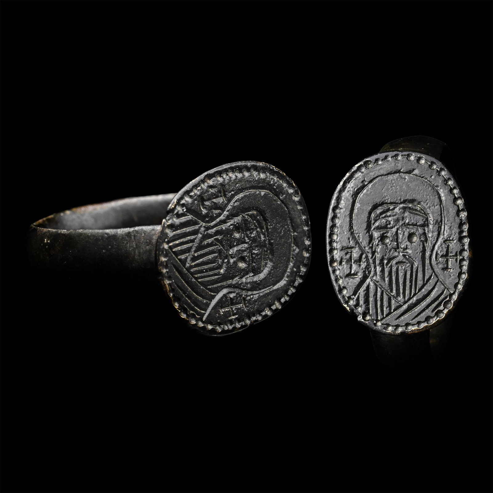 Byzantine Ring with Bust of a Saint: 12th-14th century A.D. Wide hoop with a raised boss at the base, an oval bezel with a facing bust of a nimbate saint flanked by two crosses. 5.73 grams, 23.63 mm overall, 19.84 mm internal diameter (a