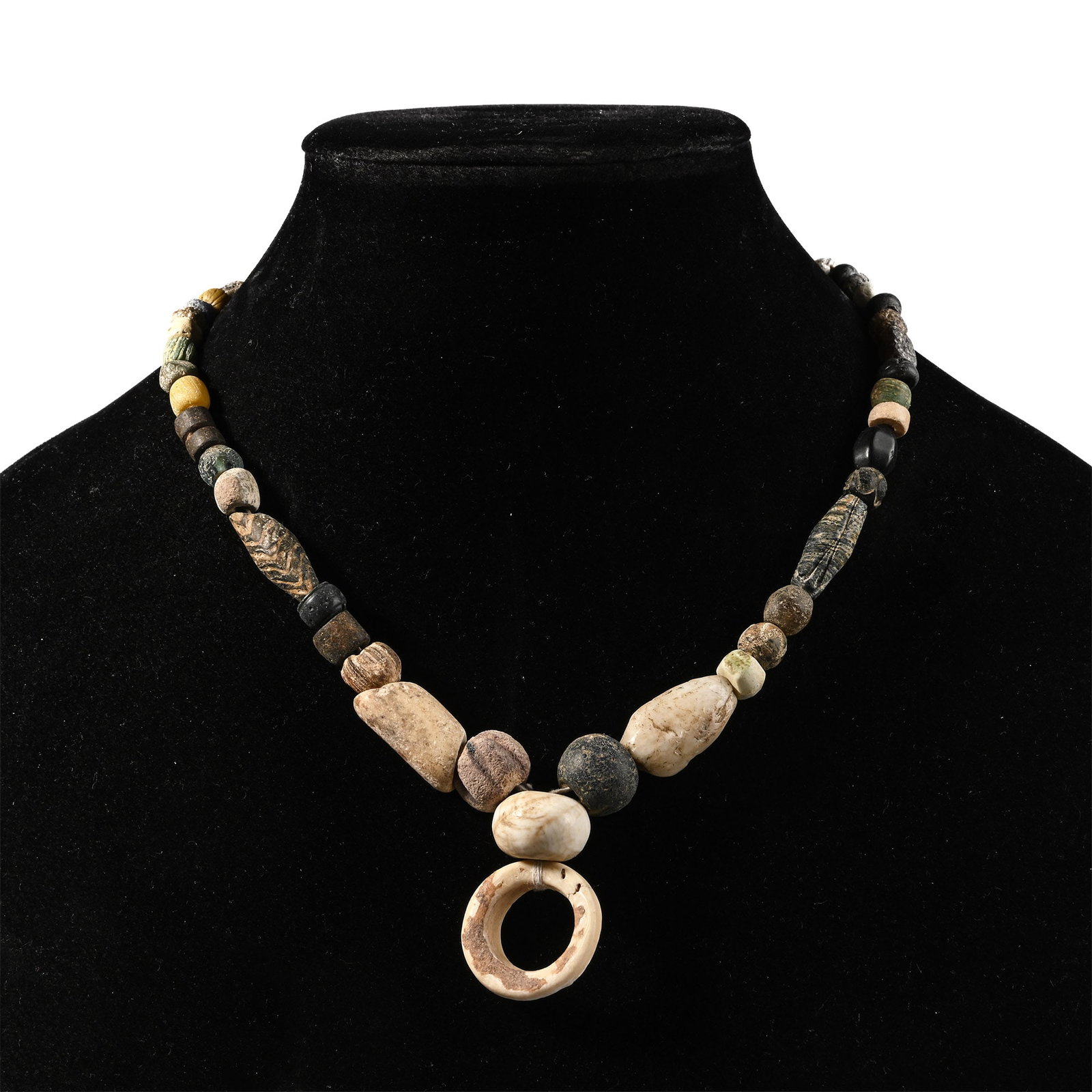 Western Asiatic Glass and Other Bead Necklace String: 1st millennium B.C. and later. Composed of oblate, biconical and other beads, the central feature a large annular bead, restrung. 60.1 grams, 44 cm (17 1/4 in.). [No Reserve] Acquired in the 1990s. Ex